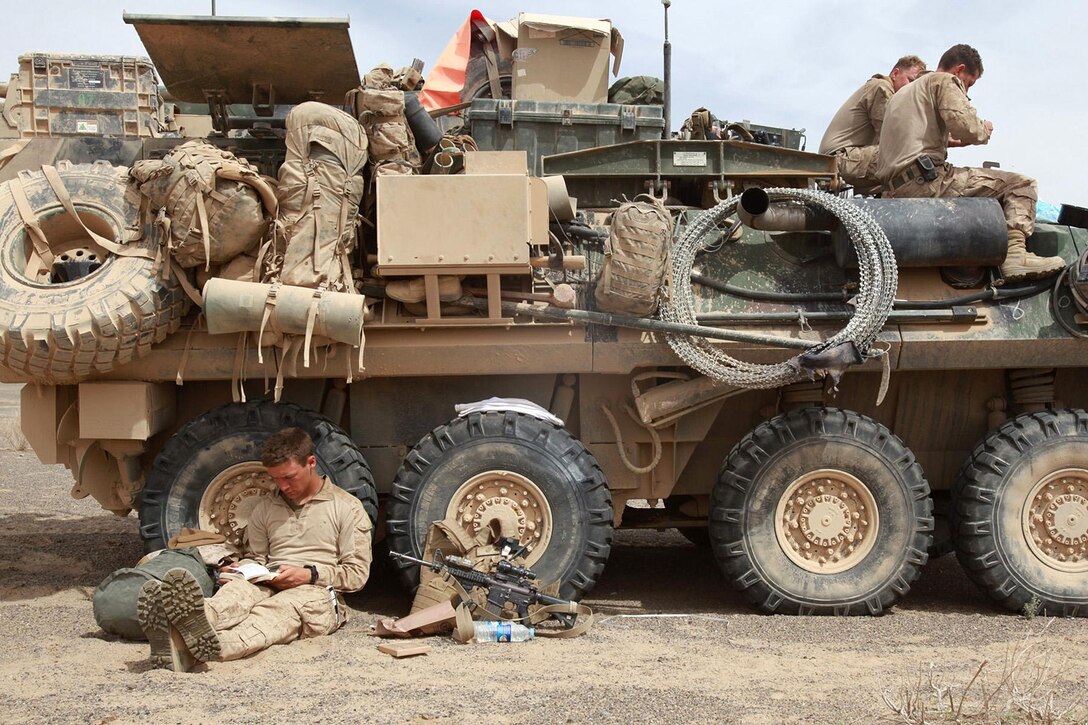 Lance Cpl. Mitchell Brady (left), a scout with C Company, 3rd Light Armored Reconnaissance Battalion and a native of Galesburg, Ill., relaxes in the shade of his light armored vehicle in southern Helmand province, Afghanistan, March 18, after a four-day raid against an insurgent stronghold on the Pakistan border. LAR Marines typically spend weeks and months away from bases, out in open country, making their vehicles a sort of mobile home during deployments.