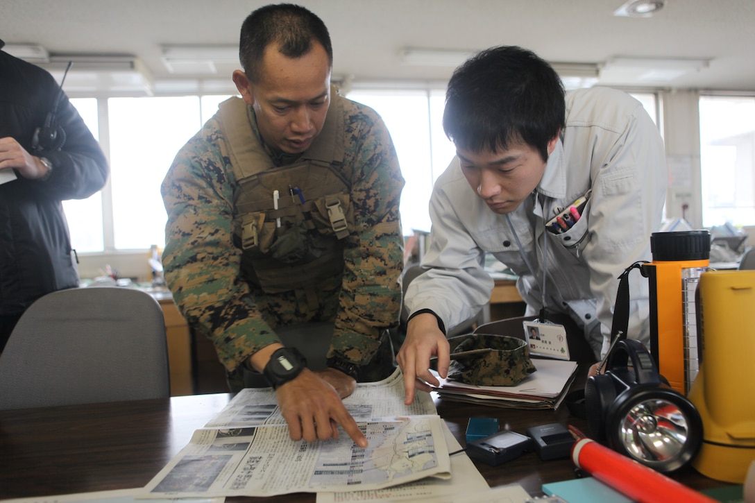 2nd Lt. Tuan Pham, a planner with Combat Logistics Battalion 31, 31st Marine Expeditionary Unit, looks over a map of disaster areas with a member of the local Japanese port authority, March 20, searching for potential landing sites which could be used for follow-on humanitarian aid operations.  The 31st MEU is preparing to provide disaster relief as part of Operation Tomodachi, and is coordinating with the ongoing Japanese relief operation to determine what areas are in need of further assistance.