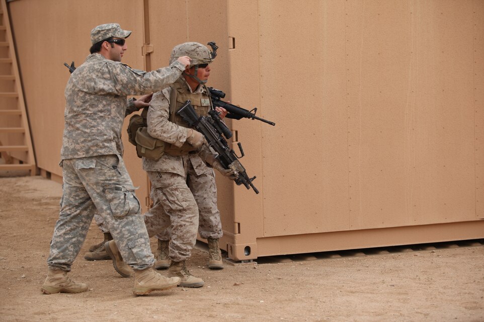 An Army Green Beret instructs two Marines to perform a house clearing exercise aboard the Combat Center’s CAMOUT facility March 19, 2011, during a Joint National Training Capabitiy program, exercise.::r::::n::