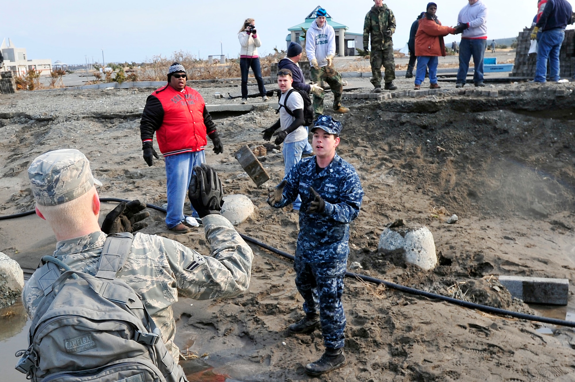 MISAWA AIR BASE, Japan -- Airmen and Sailors establish an assembly line to clean up bricks and other debris at the Misawa City fishing port and beach area Mar. 19. Daily trips of volunteers have been leaving the base since Mar. 14 to help the local community with clean-up efforts. (U.S. Air Force photo by Staff Sgt. Marie Brown\Released)

