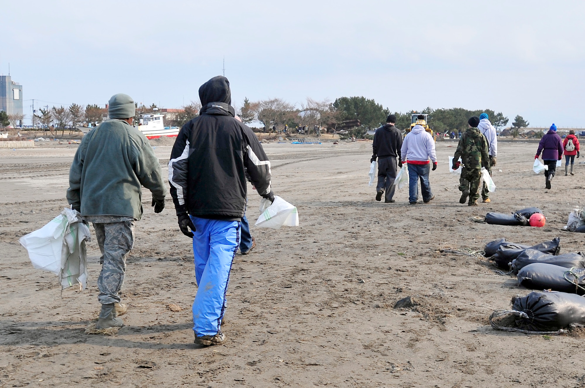 MISAWA AIR BASE, Japan -- Airmen and Sailors walk along the Misawa City fishing port Mar. 19. Volunteers have been helping with clean-up efforts since Mar. 14 after trash and debris washed up on the shoreline due to the effects of an earthquake Mar. 11. (U.S. Air Force photo by Staff Sgt. Marie Brown\Released)
