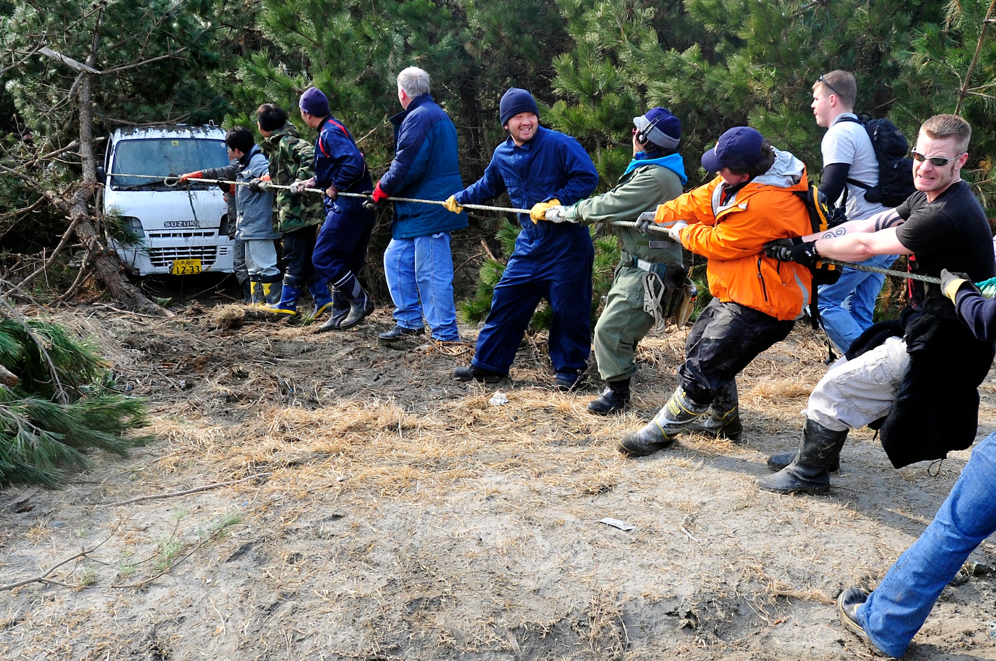 MISAWA AIR BASE, Japan - Airmen and Sailors work together with Japanese residents to pull a vehicle out of the tree line at the Misawa City fishing port Mar. 19. A tsunami washed vehicles, trash and debris into the tree line after an earthquake hit northern Japan Mar. 11. (U.S. Air Force photo by Staff Sgt. Marie Brown\Released)
