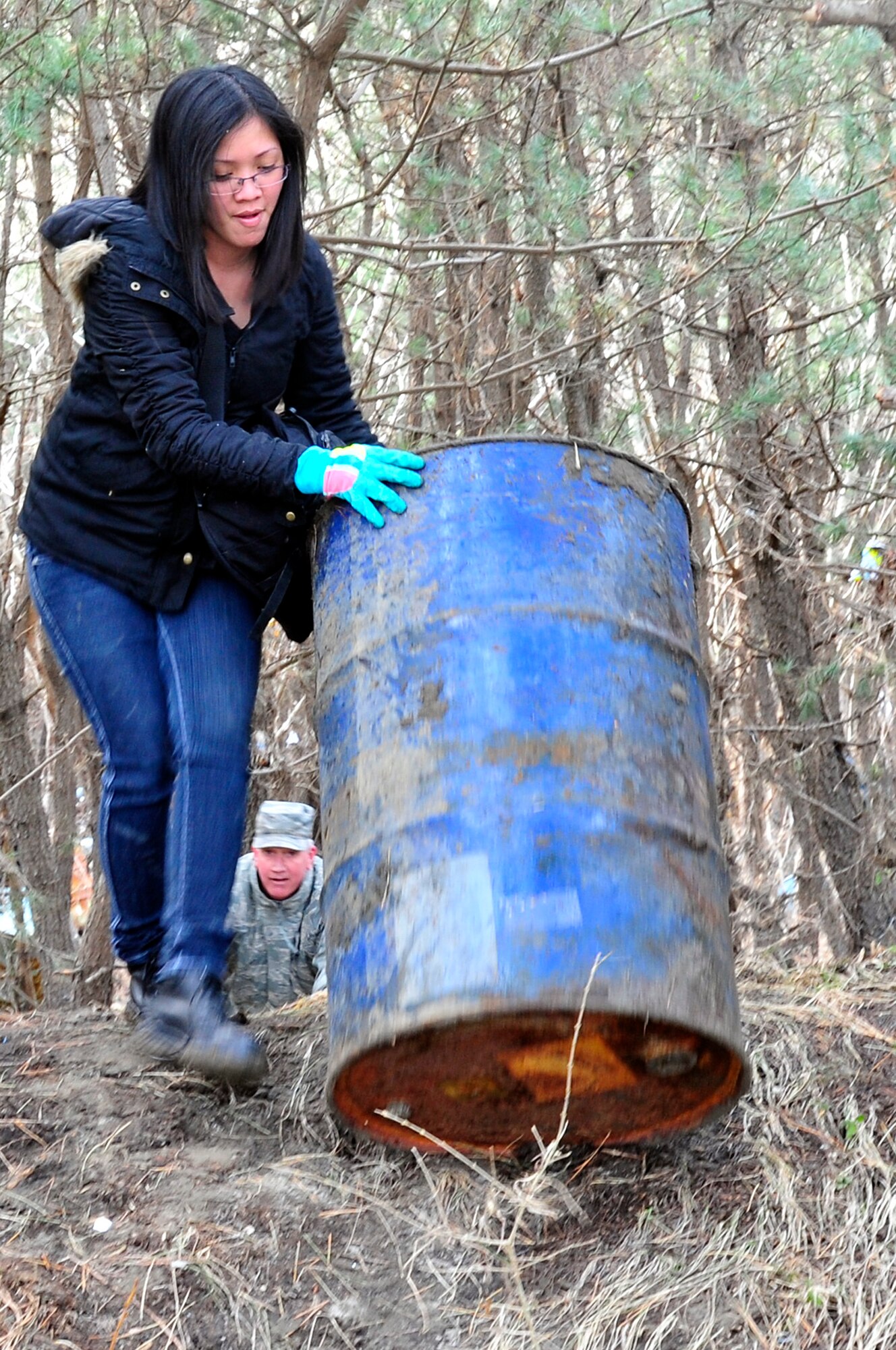 MISAWA AIR BASE, Japan -- Amy Casten rolls a barrel out of the tree line while volunteering at the Misawa City fishing port Mar. 19. More than 600 Misawa residents have stepped up to volunteer in the local community after a tsunami washed trash and debris up on the shore Mar. 11. (U.S. Air Force photo by Staff Sgt. Marie Brown\Released)
