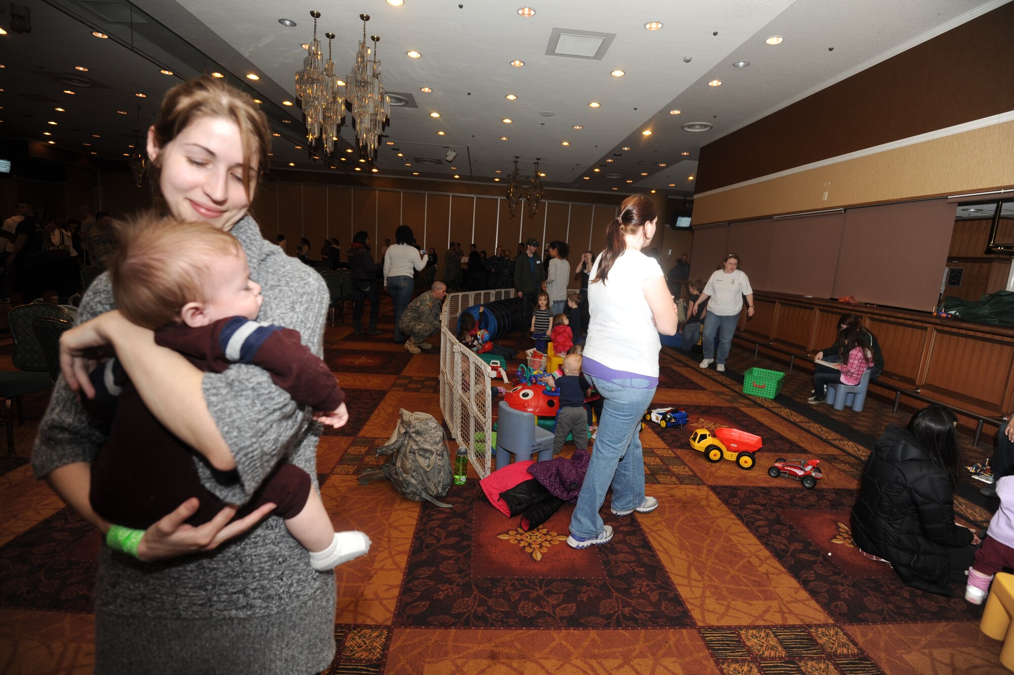 MISAWA AIR BASE, Japan -- Through all the commotion going on in the Enlisted club ballroom due to the voluntary evacuation of Misawa Air Base family members, young 7 month old Regal Flores decides to take a nap in the safe arms of his mother Ashley Flores on March 19.  Mrs. Flores has decided to leave voluntarily so that her husband can focus on his job and volunteering to help the local community, without worrying about their safety.  (U.S. Air Force photo by Staff Sgt. April Quintanilla\Released)