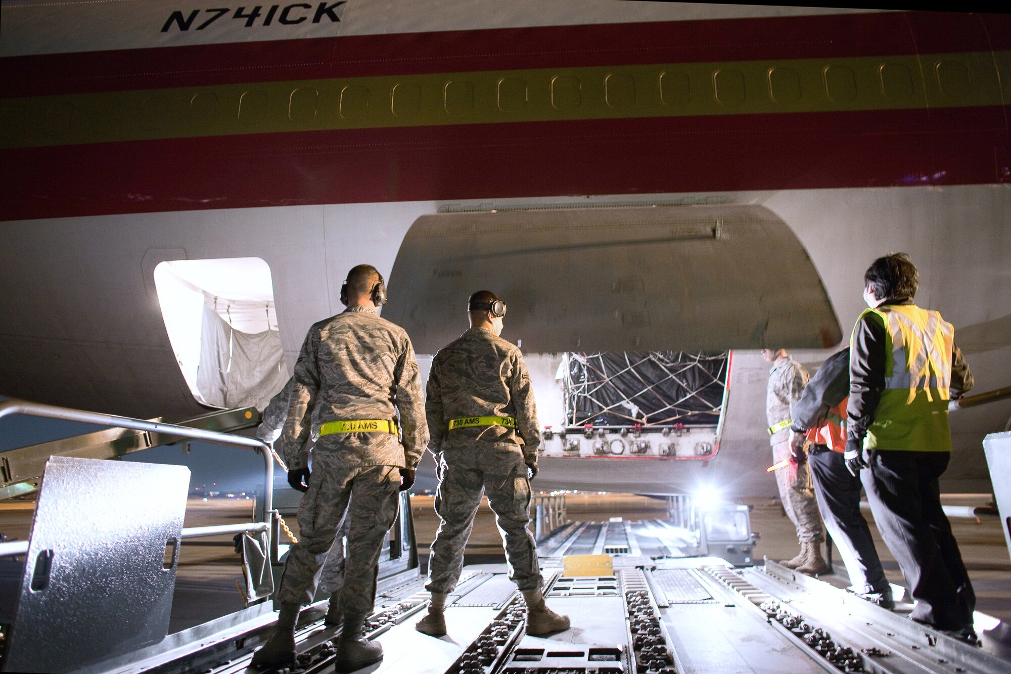 YOKOTA AIR BASE, Japan -- Members of the 730th Air Mobility Squadron wait to unload supplies on a K-loader here March 19. An international charter aircraft delivered 95 tons of blankets, plastic sheeting, hygiene supplies, soap and jerry cans to assist with earthquake and tsunami relief efforts. (U.S. Air Force photo/Osakabe Yasuo)
