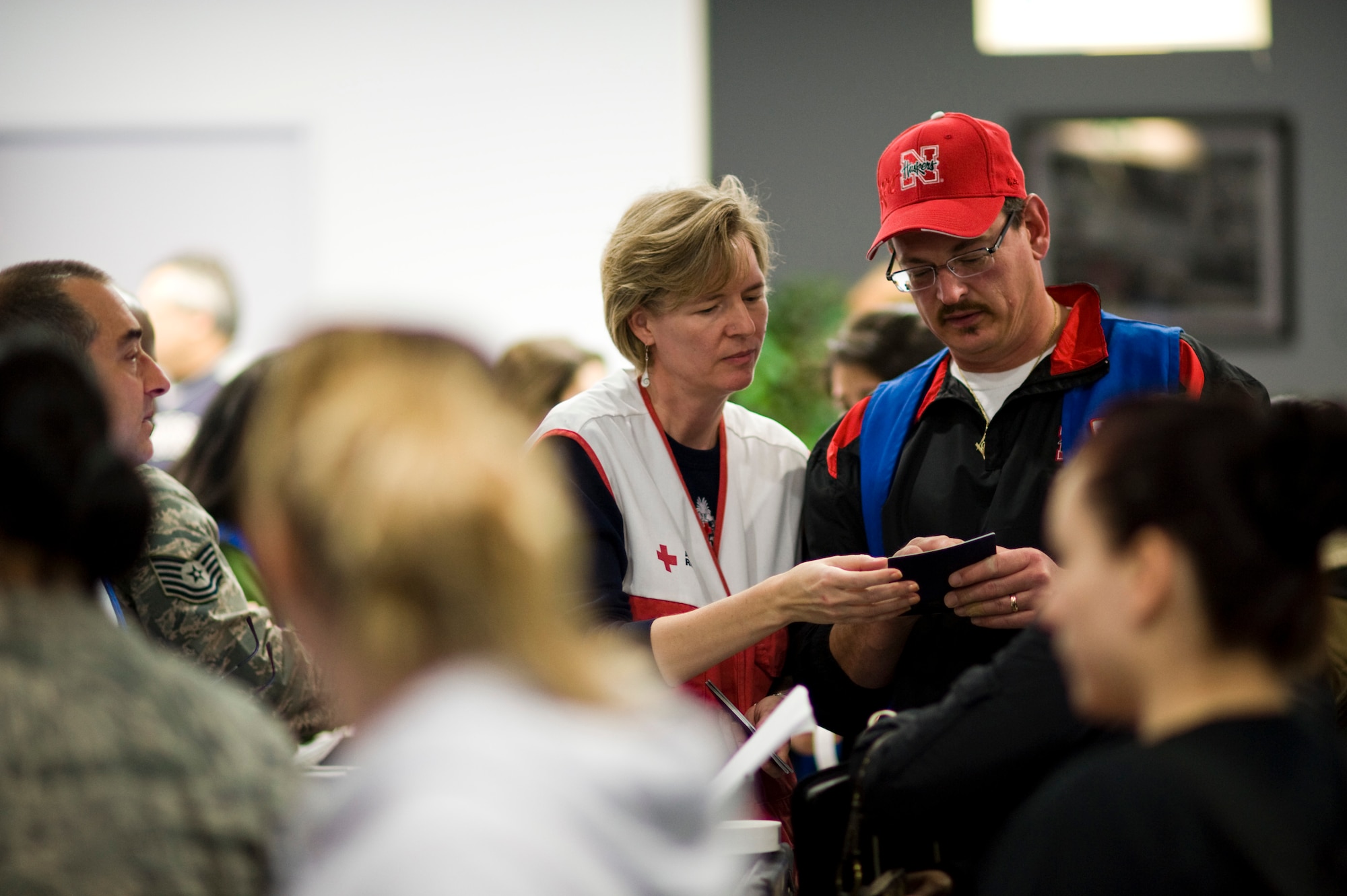 YOKOTA AIR BASE, Japan -- Two Red Cross volunteers review a passport during a large scale out-processing here, at the Taiyo Community Center, March 19. Military dependants participated in the first wave of voluntary authorized departures.  These precautionary measures are intended to help ensure the safety of U.S. citizens during this dynamic time, as well as to assist and expedite Japanese recovery efforts by reducing the demand for food, water, fuel and electricity during this national emergency in Japan. (U.S. Air Force Photo/Staff Sgt. Samuel Morse)