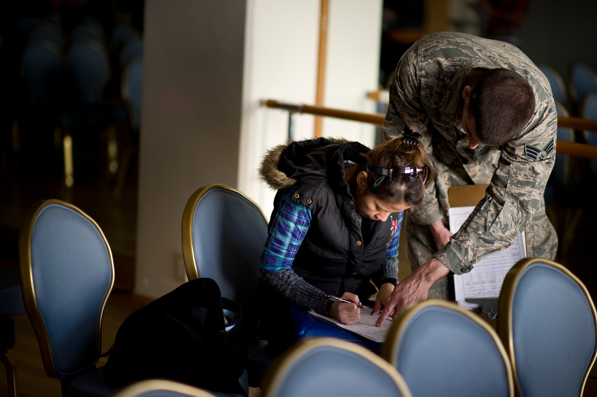 YOKOTA AIR BASE, Japan -- A Senior Airman helps a military spouse complete her Form 178 here, at the Taiyo Community Center, March 19. Military dependants participated in the first wave of voluntary authorized departures.  These precautionary measures are intended to help ensure the safety of U.S. citizens during this dynamic time, as well as to assist and expedite Japanese recovery efforts by reducing the demand for food, water, fuel and electricity during this national emergency in Japan. (U.S. Air Force Photo/Staff Sgt. Samuel Morse)