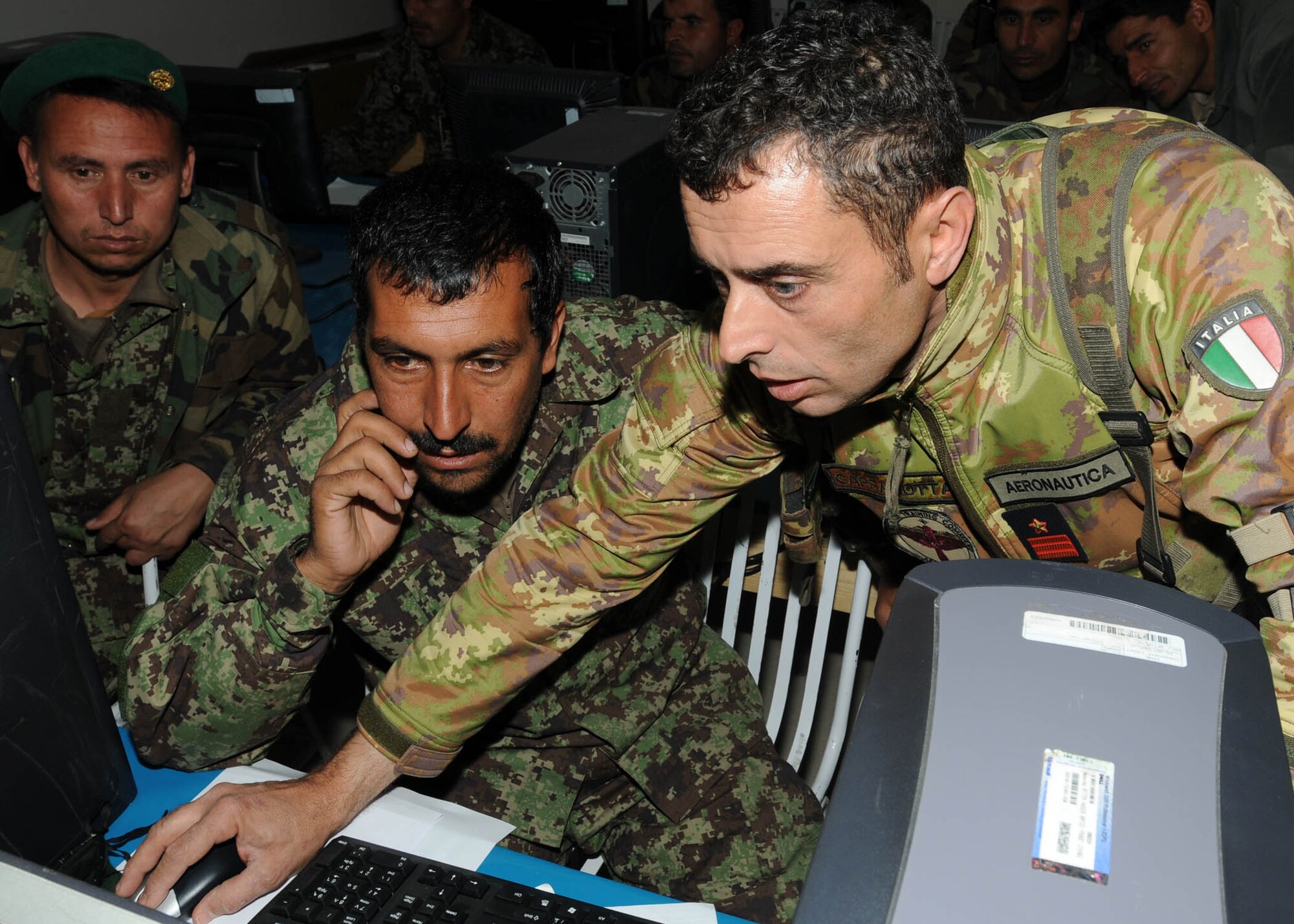 SHINDAND, Afghanistan - Italian Air Force service member, with NATO Training Mission - Afghanistan / 838th Air Expeditionary Advisory Group, teaches members of the Afghan Air Force how to use a computer in Shindand, Afghanistan. (U.S. Navy photo by Mass Communications Specialist 3rd Class Jared E. Walker).