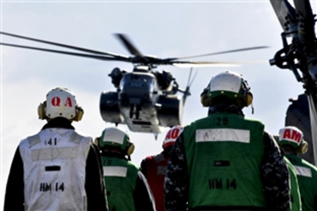 U.S. Navy sailors watch as an HM-53E Sea Dragon carrying supplies arrives on USS Tortuga in Ominato Bay, Japan, March 18, 2011. The Tortuga is currently in the 7th Fleet area of operations supporting Operation Tomodachi. The sailors are assigned to the Tortuga and the crewmen are assigned to Helicopter Anti-Submarine Squadron 14 Detachment 1.
