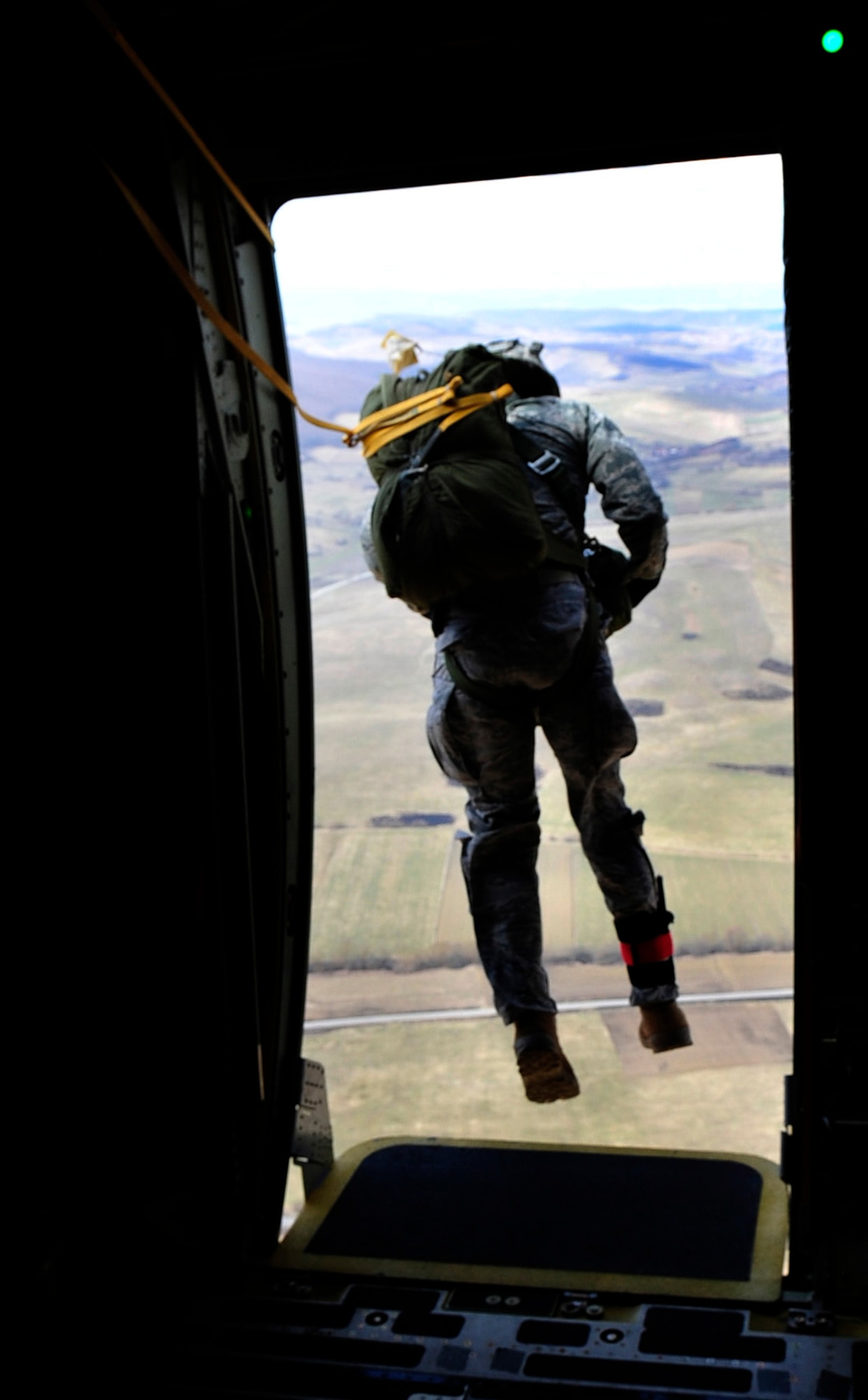 U.S. Air Force Staff Sgt. Stephen Baker, 435th Security Forces Squadron, jumpmaster, exits a troop door of a C-130J during a static jump over a landing zone near Campia Turzii, Romania, March 18, 2011.  This jump was conducted as a part of Carpathian Spring 2011, a building partnership capacity exercise where members of U.S. military joined their Romanian counterparts to learn from one another and strengthen alliances. (U.S. Air Force Photo by Tech Sgt. Jocelyn L. Rich)(released)