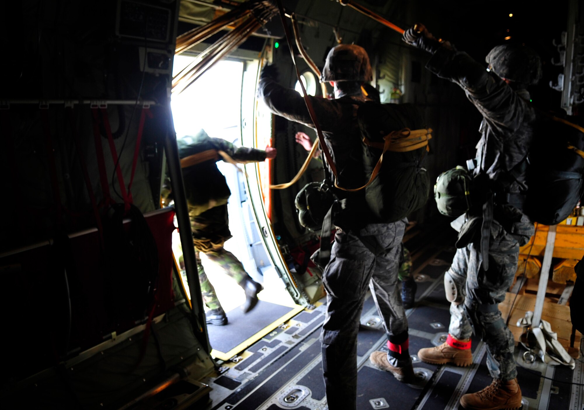 A Romanian paratrooper exits the troop door of a U.S. Air Force C-130J, under the direction of U.S. Air Force Staff Sgt. Stephen Baker, and Maj. Jason Medsger, 435th Security Forces Squadron, March 18, 2011.  This jump was conducted as a part of Carpathian Spring 2011, a building partnership capacity exercise where members of U.S. military joined their Romanian counterparts to learn from one another and strengthen alliances. (U.S. Air Force Photo by Tech Sgt. Jocelyn L. Rich)(released)