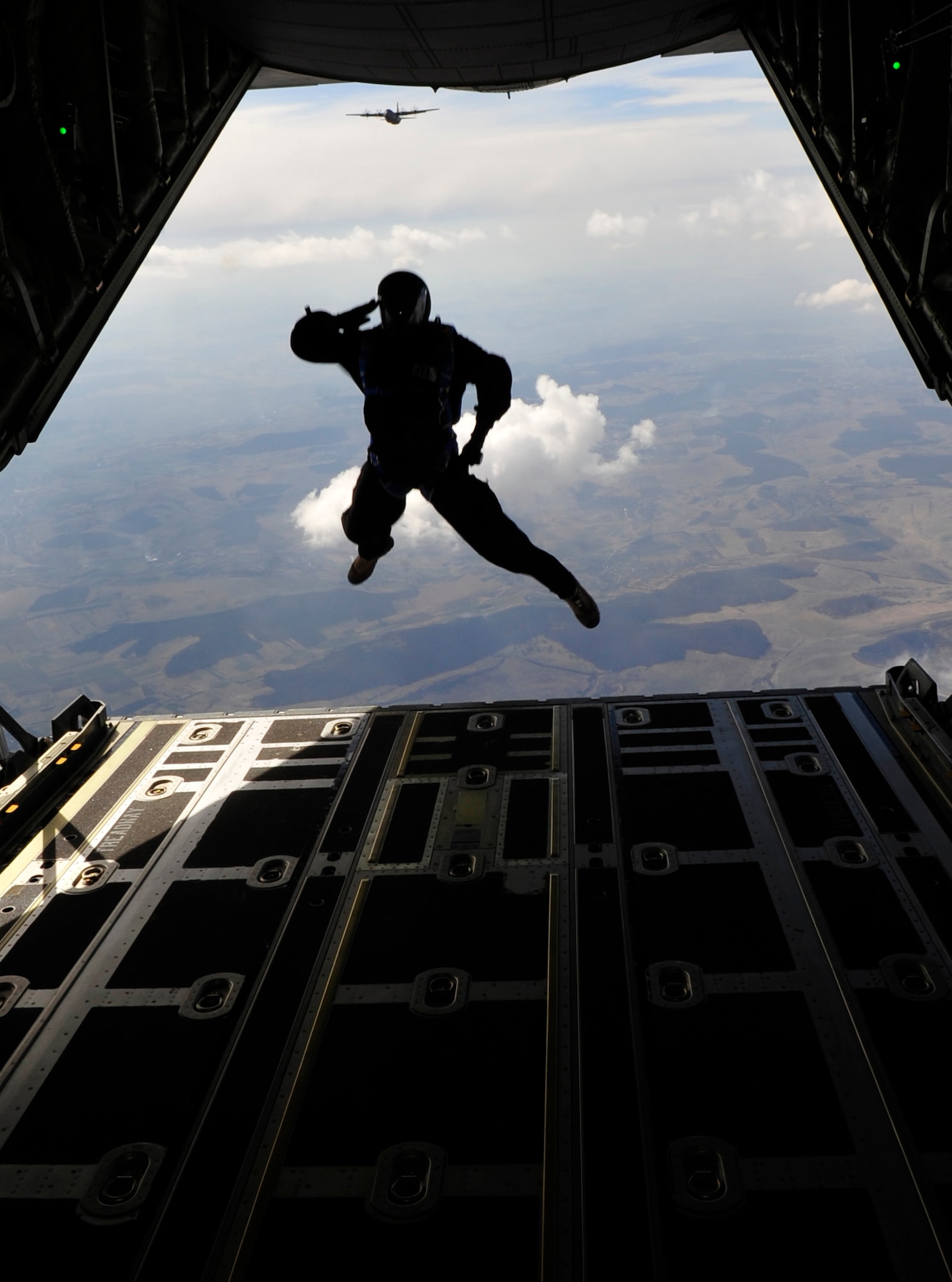 U.S. Air Force Master Sgt. Robert Zackery, 4th Air Support Operations Group, military free fall jump master, renders a salute as he exits a C-130J during a combined high altitude, low open, jump over a landing zone near Campia Turzii, Romania, March 18, 2011.  This jump was conducted as a part of Carpathian Spring 2011, a building partnership capacity exercise where members of U.S. military joined their Romanian counterparts to learn from one another and strengthen alliances. (U.S. Air Force Photo by Tech Sgt. Jocelyn L. Rich)(released)