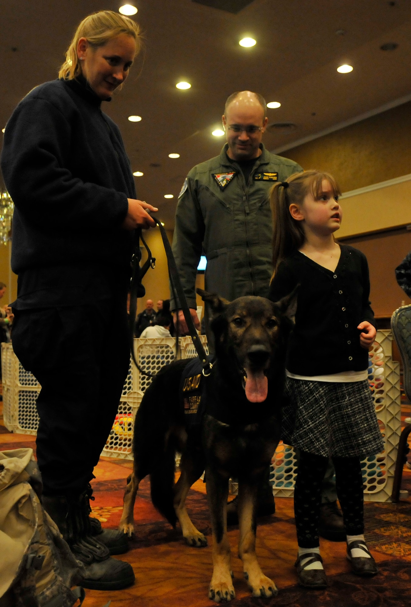 MISAWA AIR BASE, Japan -- U.S. Navy Chief Petty Officer Jason Van Buren, CTF-72 operations leading chief petty officer and his daughter Isabla, check out Atticus and his handler Jennifer Massey. Jennifer and Atticus are members of the Fairfax County, Va., urban search and rescue team that arrived here with other U.S. Agency of International Development workers. (U.S. Air Force photo by Tech. Sgt. Phillip Butterfield/Release)