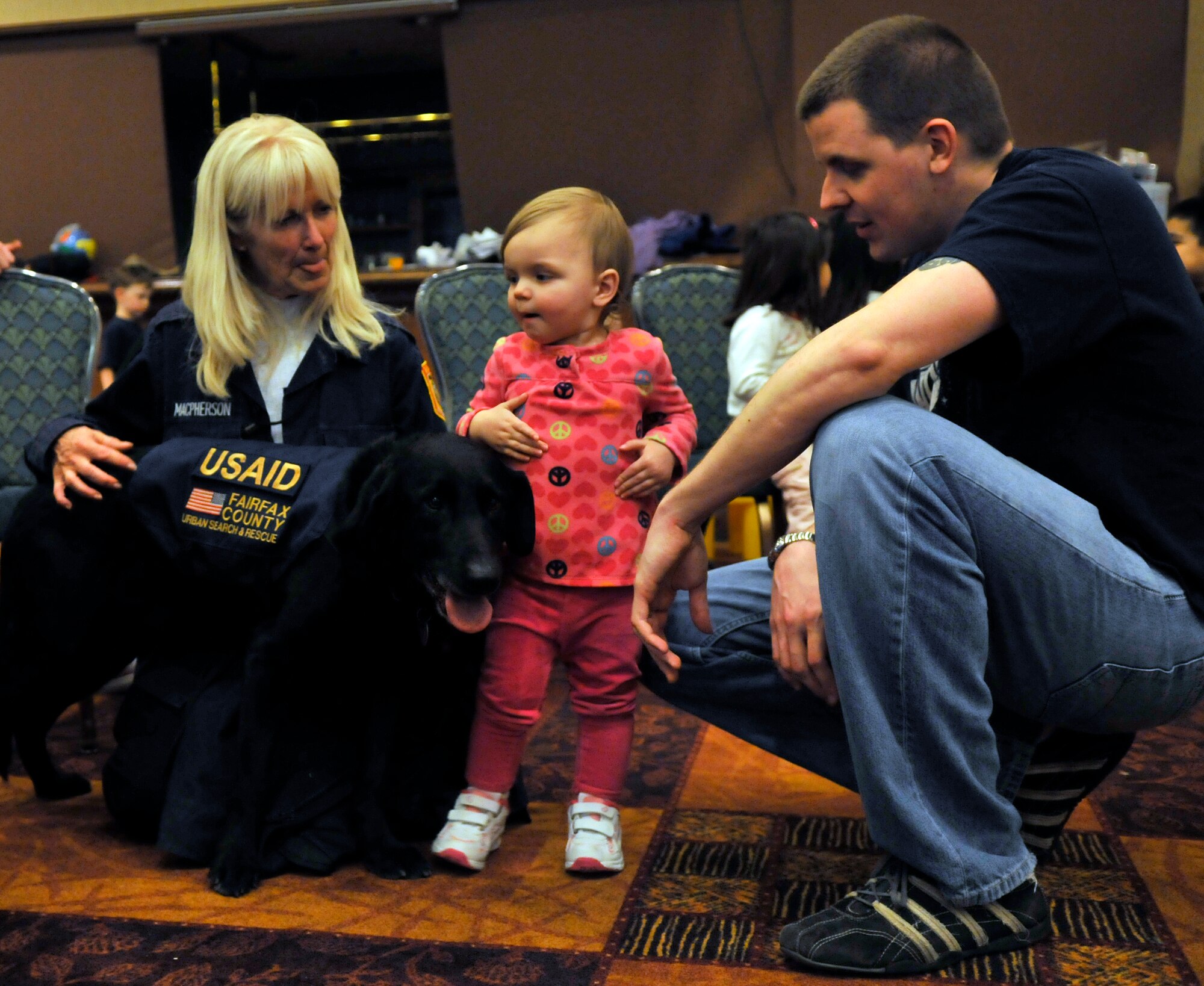 MISAWA AIR BASE, Japan -- U.S. Agency for International Development dog handlers brought their working dogs to the collocated club to entertain the children as their parents wait in the voluntary departure processing lines Mar. 19. After completing their mission here in Japan, the team headed back to the U.S. (U.S. Air Force photo by Tech. Sgt. Phillip Butterfield/Release) 