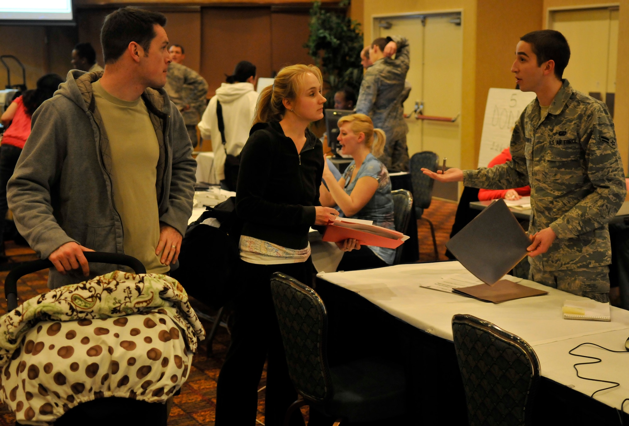 MISAWA AIR BASE, Japan -- U.S. Air Force Capt. Cole Taylor, 35th Medical Operations Squadron physician and his wife, Breanne, listen to Airman First Class Timothy Whitworth, 35th Comptroller Squadron customer service technician, explain the per diem rules that apply to the voluntary departure process Mar.19. Many travelers expressed their gratitude of how well the process worked. (U.S. Air Force photo by Tech. Sgt. Phillip Butterfield/Release)