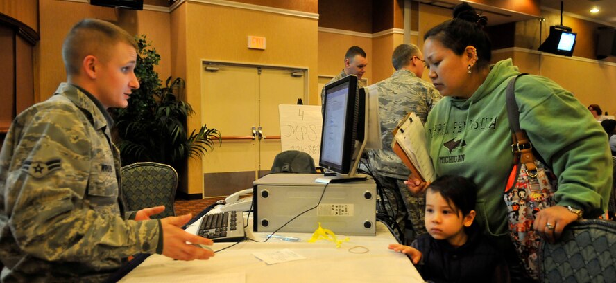 MISAWA AIR BASE, Japan -- Jennifer Tengco and her son Cameron Carlson, listen as U.S. Air Force Airman First Class William Wroten, 373rd Support Squadron client systems technician, as he pitches the Red Cross's tracking data base Mar. 19. The Red Cross uses a data system that people can access to determine a passenger’s location. Mrs. Tengco is the wife of U.S. Navy Petty Officer Kyle Carlson. (U.S. Air Force photo by Tech. Sgt. Phillip Butterfield/Release)