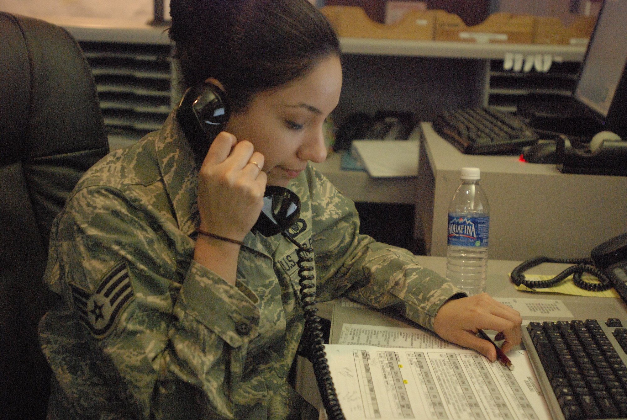 Staff Sgt. Jenny Sanchez answers questions about flight plans in the 433rd Airlift Wing command post. Members here act as the wing nerve center for wing information and operations.  The Alamo Wing command post was named the 4th Air Force Small Conventional Command Post of the Year and is in competition for the Air Force Reserve Command award. (U.S. Air Force photo/Senior Airman Brian McGloin)