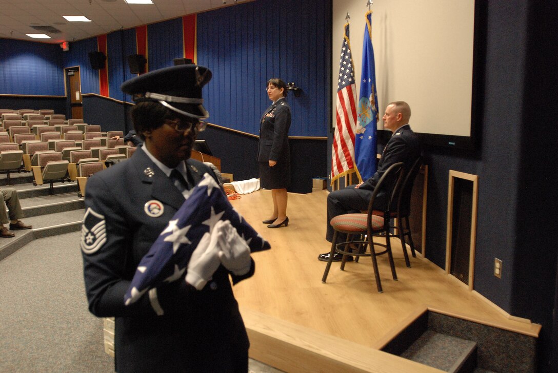 Master Sgt. Patricia Bush, 433rd Force Support Squadron honor guard superintendent, carries a folded American flag to Maj. Elena Milford, 433rd Airlift Wing Public Affairs chief, during her retirement ceremony in the 68th Airlift Squadron auditorium, Lackland Air Force Base, Texas. (U.S. Air Force photo/Senior Airman Brian McGloin)