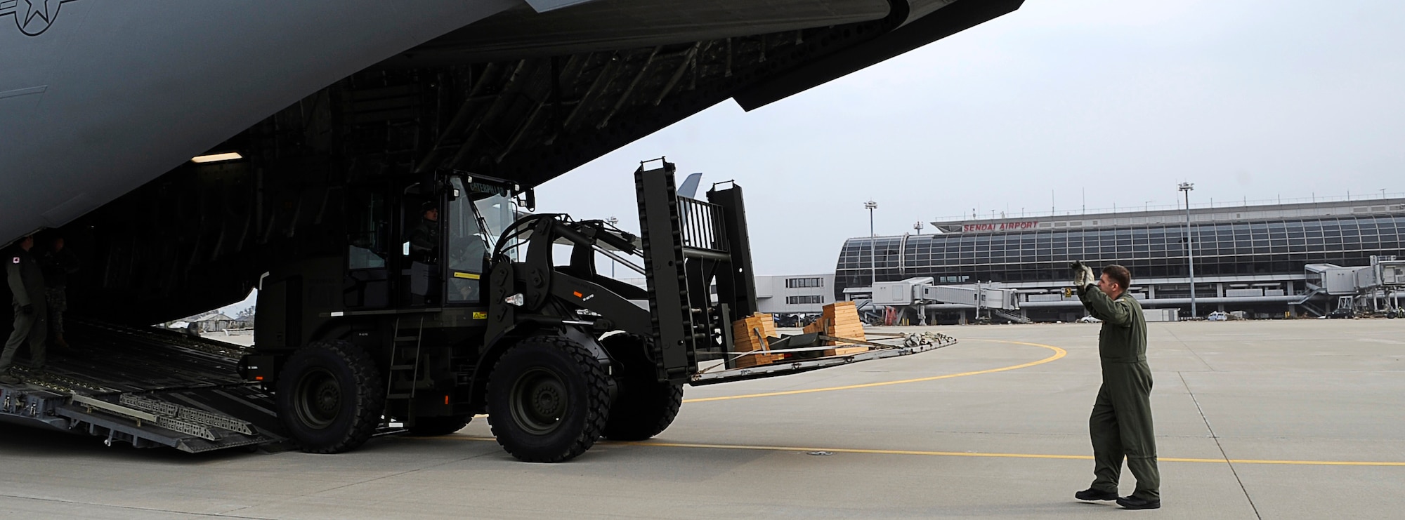 SENDAI AIRPORT, Japan -- U.S. Air Force Airmen from Yokota, Air Base unload rolling stock from a C-17 Globemaster III aircraft March 20. This was the first C-17 to land here after the tsunami. (U.S. Air Force photo by/ Master Sgt. Jeromy K. Cross/Released)