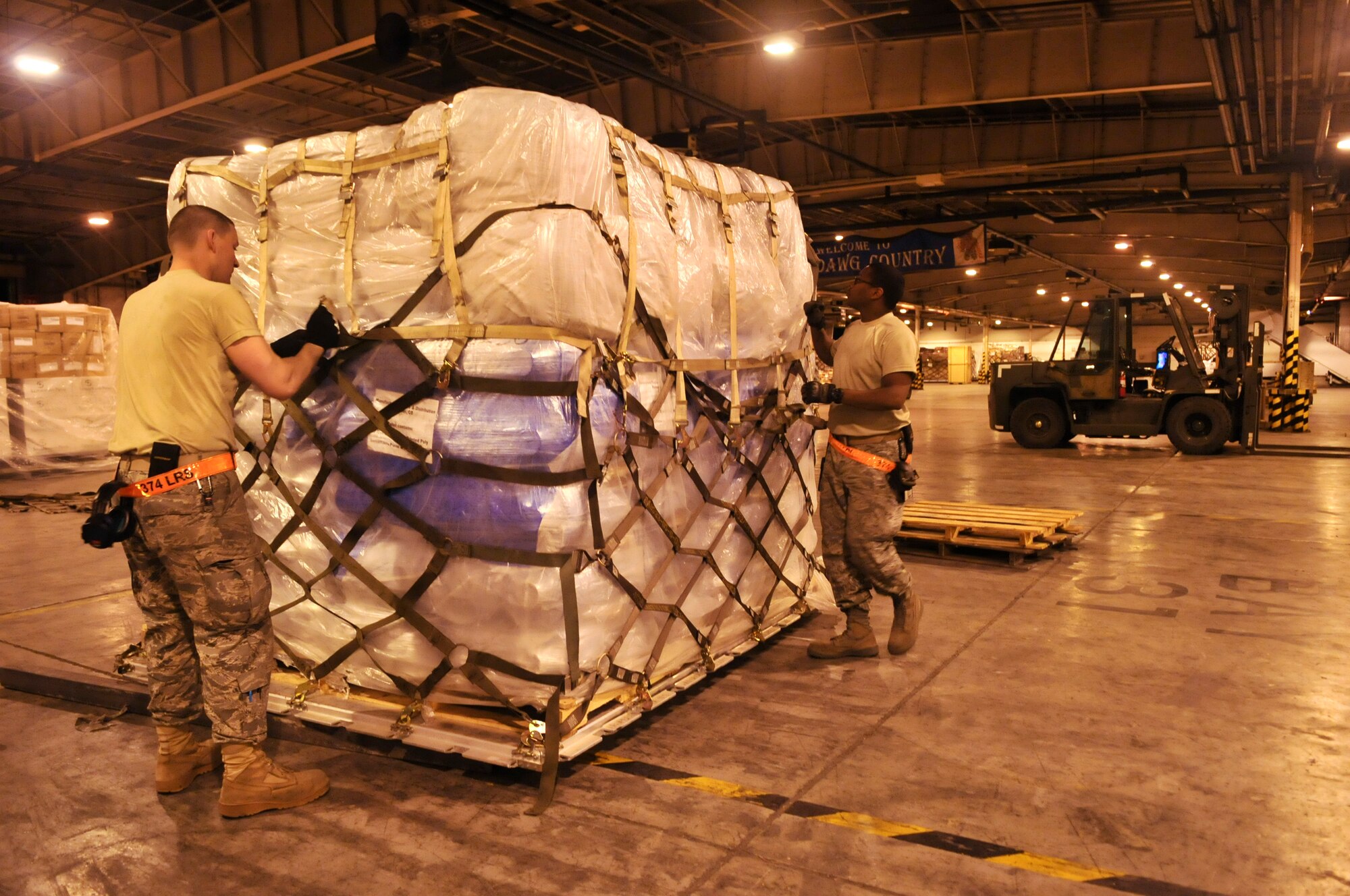 YOKOTA AIR BASE, Japan -- Airman 1st Class James Carr and Staff Sgt. Warren Smith, 374th Logistics Readiness Squadron air transportation specialists, secure a pallet of blankets inside a cargo warehouse here March 20. The relief supplies are scheduled to be delivered to support Operation Tomodachi. (U.S. Air Force photo/Airman 1st Class Andrea Salazar)(Released)