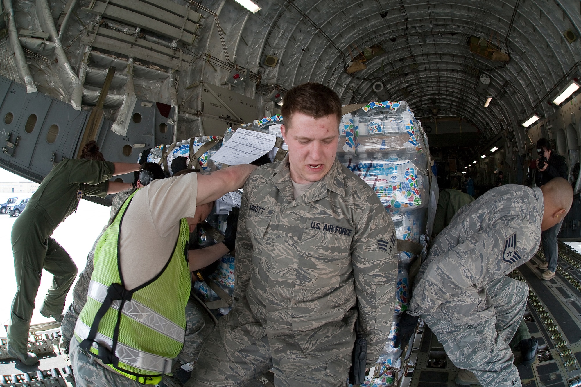 YOKOTA AIR BASE, Japan -- Senior Airman Nicholas Abbott (center), 730th Air Mobility Squadron, pushes a pallet of water bottles onto a C-17 Globalmaster III here March 20. The pallet was part of the the first humanitarian relief supplies being delivered to Sendai. (U.S. Air Force photo/Osakabe Yasuo)(Released)