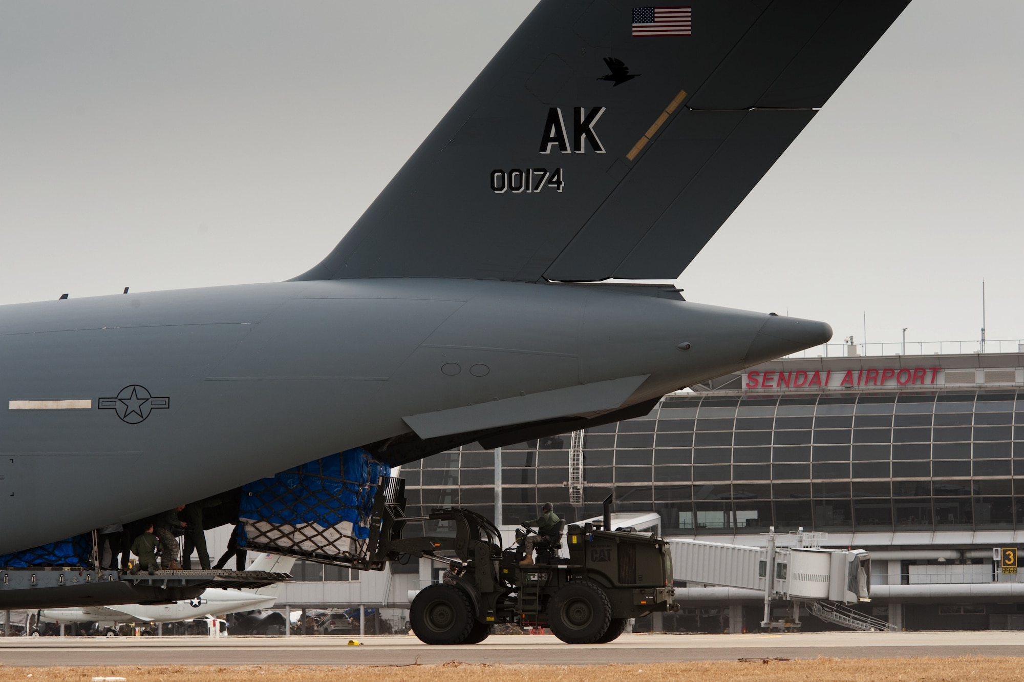 SENDAI AIRPORT, Japan -- Members of the 353rd Special Operations Group from Kadena Air Base, Japan, unload the first pallet of humanitarian aid from the first C-17 Globemaster II here March 20. Members of the 320th Special Tactics Squadron from Kadena Air Base, Japan, reopened the runway to fixed-wing aircraft March 16 and cleared the rest of the runway to accommodate larger aircraft such as the C-17, enabling larger shipments of humanitarian aid to help those affected by the earthquake and tsunami of March 11. (U.S. Air Force photo/Staff Sgt. Samuel Morse)