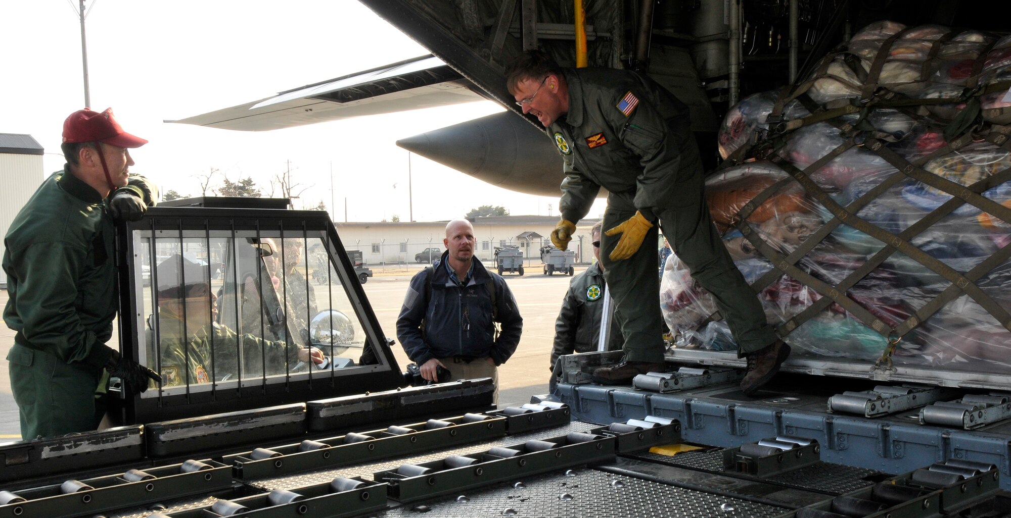 MISAWA AIR BASE, Japan -- U.S. Navy Reserve Senior Chief Mike Wendillen, C-130 Hercules load master, directs the Japan Air Self-Defense Force cargo load-truck driver to realign the vehicle Mar. 19. The C-130 Hercules is just one type of aircraft seen in the skies over Misawa Air Base delivering humanitarian relief supplies. (U.S. Air Force photo by Tech. Sgt. Phillip Butterfield\Released)  