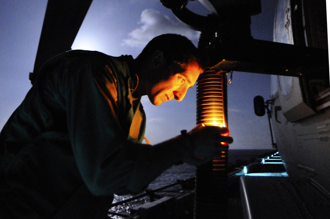 U.S. Navy Petty Officer 2nd Class Jordan Orr checks the mount for a GAL-21 machine gun on a MH-60S Knight Hawk helicopter on the flight deck of amphibious assault ship USS Kearsarge to prepare for Operation Odyssey Dawn missions in the Mediterranean Sea, March 19, 2011. Orr is assigned to Helicopter Sea Combat Squadron 22.