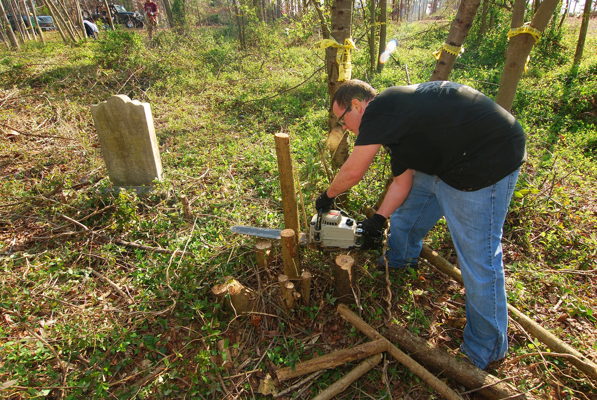 Chase Waters, a volunteer assisting with the Jonesville cemetery cleanup, clears away small tree stumps near a grave on Dobbins Air Reserve Base.  The cleanup was organized by the Dobbins Human Resource Development Council and Top Three Association with help from Marietta Mount Sinai Baptist Church members.  The cemetery is located on Dobbins ARB but was not part of the government property purchase in the early 1940s and is now the subject of extensive research to determine who owns the property.  (U.S. Air Force photo/ Brad Fallin)