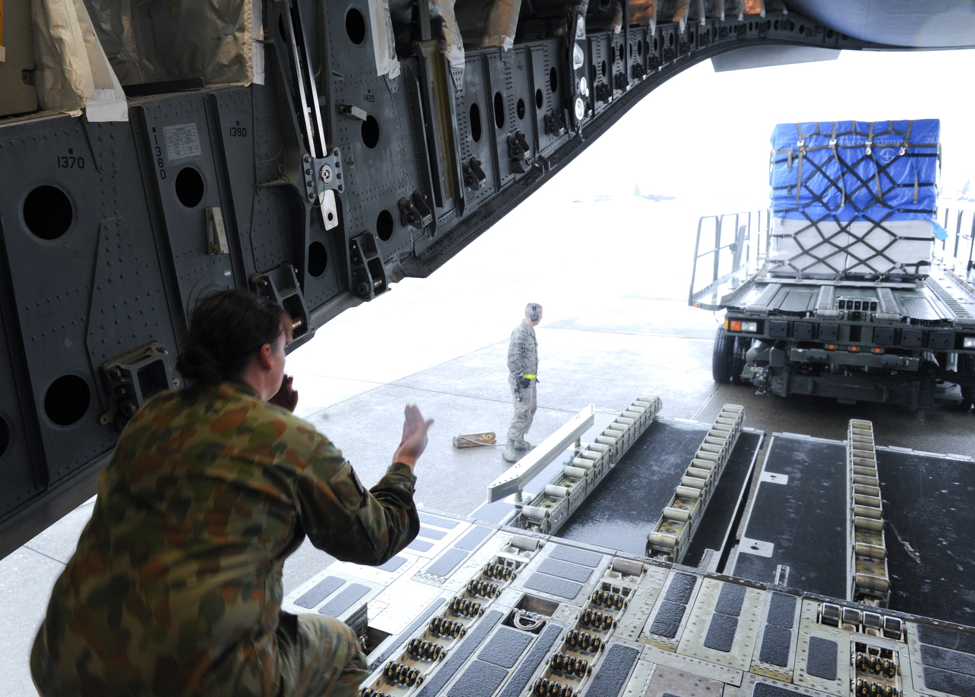 YOKOTA AIR BASE, Japan -- Royal Australian Air Force Leading Aircraft Woman Robyn Lamont, air movement technician, marshals humanitarian aid on to a C-17 Globemaster III March 21. With the assistance of Yokota Airmen, the RAAF delivered 16 pallets of humanitarian aid to Sendai, Japan, in support of Operation Tomodachi. Operation Tomodachi is a relief support mission aiding those affected by the devastation caused by the recent earthquake and tsunami March 11. (U.S. Air Force photo/Senior Airman Michael J. Veloz)