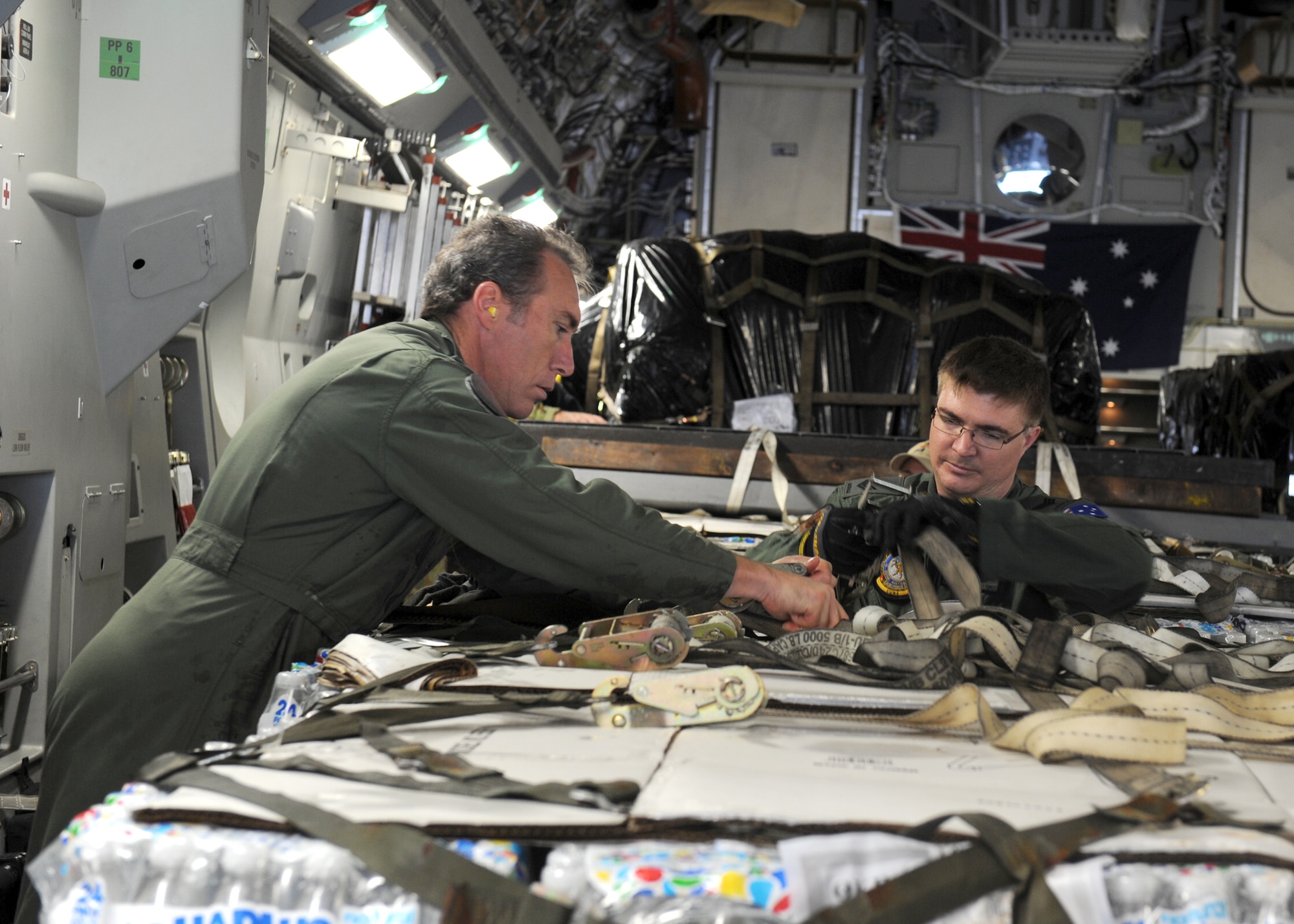 YOKOTA AIR BASE, Japan -- Warrant Officer Ray Maconachie (left) and Sergeant Chris Voight tighten down pallets in a C-17 Globemaster III from Royal Australian Air Force Base Amberley March 21. With the assistance of Yokota Airmen, the RAAF delivered 16 pallets of humanitarian aid to Sendai, Japan, in support of Operation Tomodachi. The two loadmasters from the RAAF 36th Squadron are here to support relief operations being conducted to help those affected by the devastation caused by the recent earthquake and tsunami March 11. (U.S. Air Force photo/Senior Airman Michael J. Veloz)
