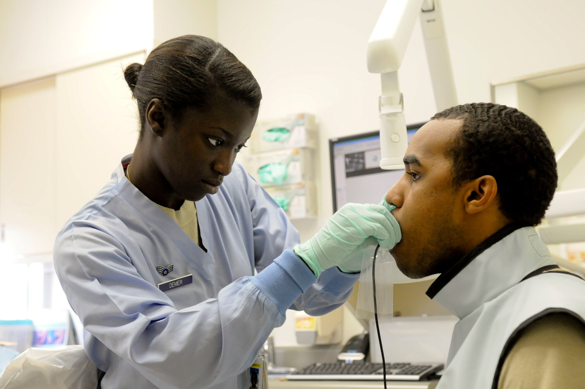 Senior Airman Allicen Demer, dental technician with the 18th Dental Squadron, prepares Airman William Odom, a member of the 18th Aerospace Medicine Squadron, to receive x-rays of his wisdom teeth, March 10. Demer sees six to eight patients a day at the Kadena dental clinic. (U.S. Air Force photo/ Airmen 1st Class Brooke P. Beers)
