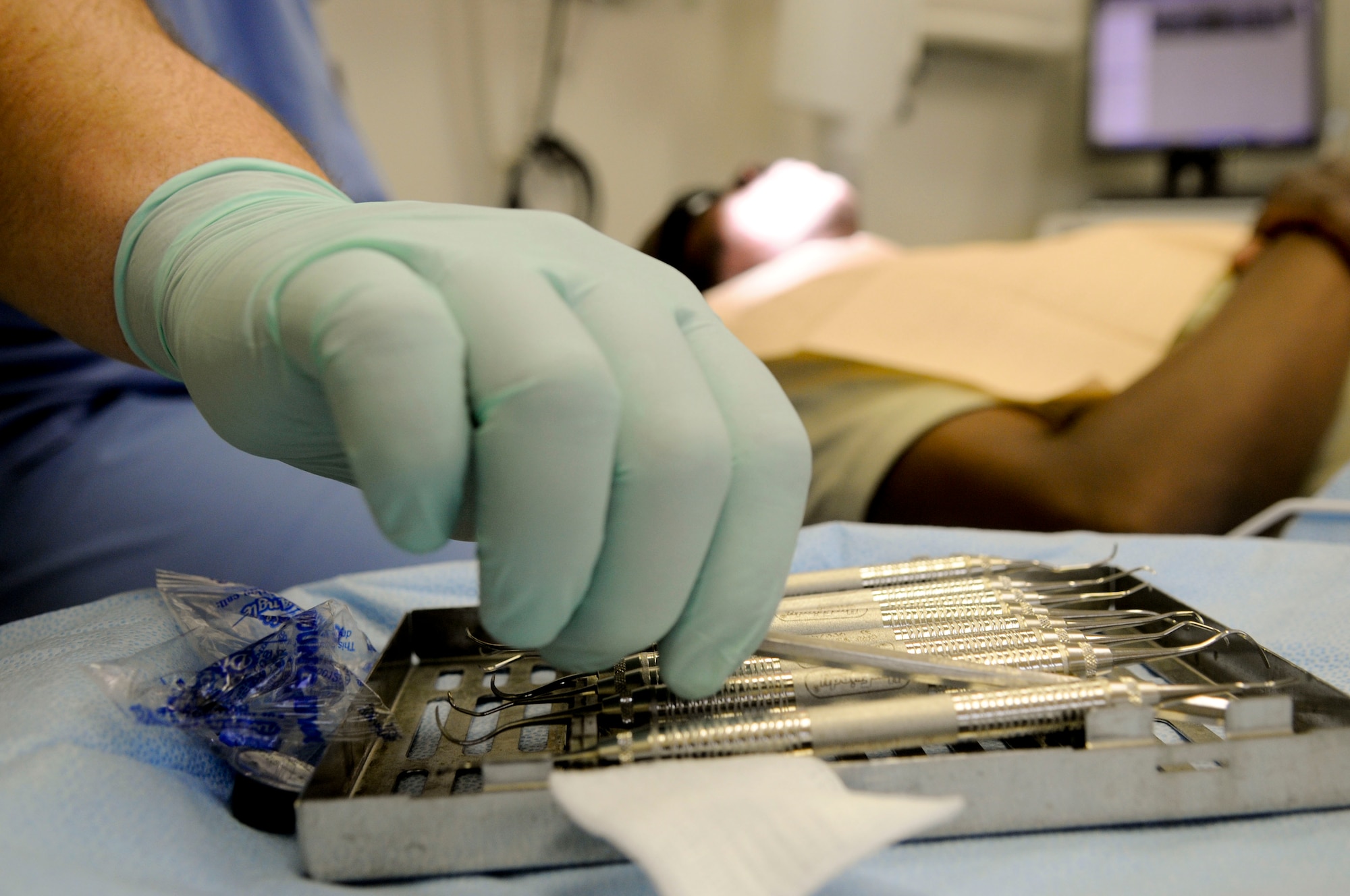 Senior Airmen Jeremy West, a dental technician with the 18th Dental Squadron, reaches for some tools while performing a routine cleaning on Chief Master Sgt. Gerald Singletary, 18th Maintenance Operations Squadron, March 10. Unlike at stateside bases, the dental clinic here treats family members as well as service members. (U.S. Air Force photo/ Airmen 1st Class Brooke P. Beers)