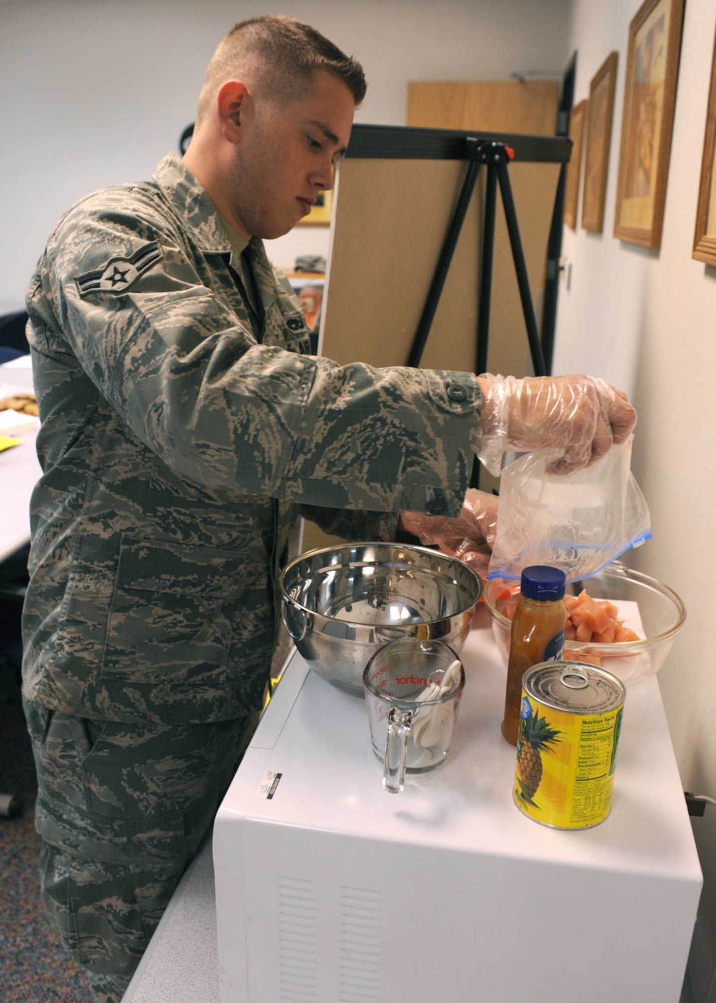 DYESS AIR FORCE BASE, Texas – Airman 1st Class Briggen Baker, 7th Aircraft Maintenance Squadron, prepares food to be cooked March 18 during a microwave cooking class at the Health and Wellness Center here. The class is designed to teach dorm residents the flexibility of microwave cooking so they're not bound to the dining facility. Airmen learned to cook cinnamon rolls, chicken dip and sweet and sour chicken. Dyess Health and Wellness Center is offering nutrition bingo March 24 from 5-6 p.m., kids healthy snack class March 25 from 10-11 a.m. and a snack bar challenge that ends March 25 as part of National Nutrition Month. For more information, visit the HAWC at the fitness center or call (325) 696-4140. (U.S Air Force Photo/ Senior Airman Chelsea Cummings)
