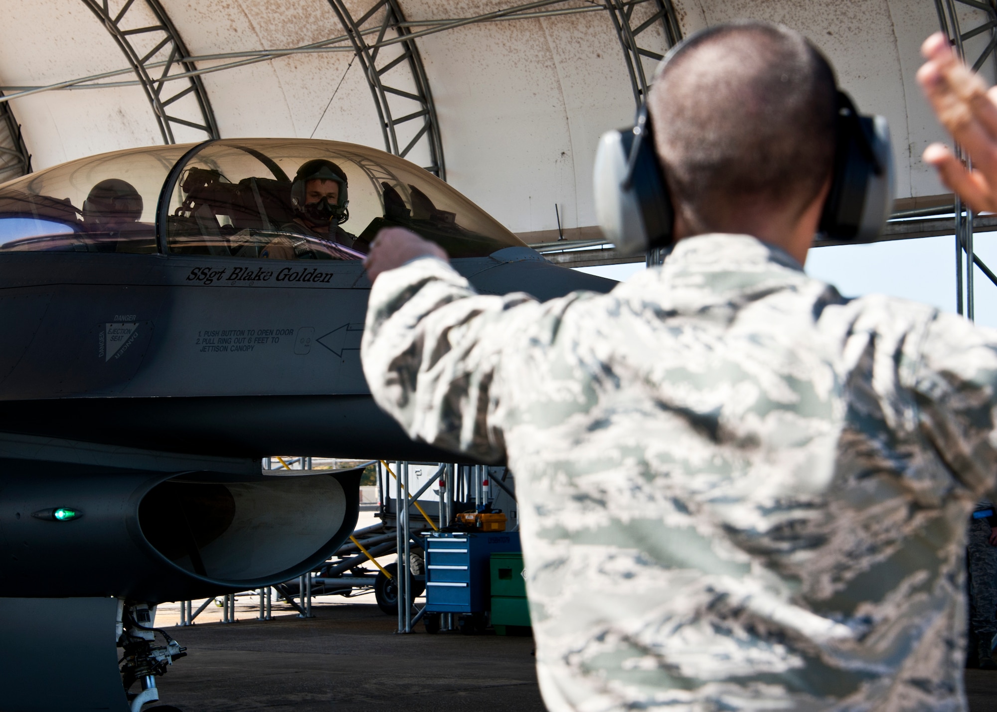 Marine Lt. Col. James Wellons, Marine Fighter Attack Training Squadron 501 commander, begins to roll as Airman 1st Class Andrew Merriman, 56th Aircraft Maintenance Squadron, leads him out of the hangar at Eglin Air Force Base, Fla., March 18.  The F-16 sorties flown by Marine pilots last week were the first flights for the VMFAT-501 - the Marine squadron responsible for training on the F-35B.  The flights are designed to familiarize the pilots with an aircraft similar to the F-35 as well as introduce them to the airspace and flightline operations.  (U.S. Air Force photo/Samuel King Jr.)
