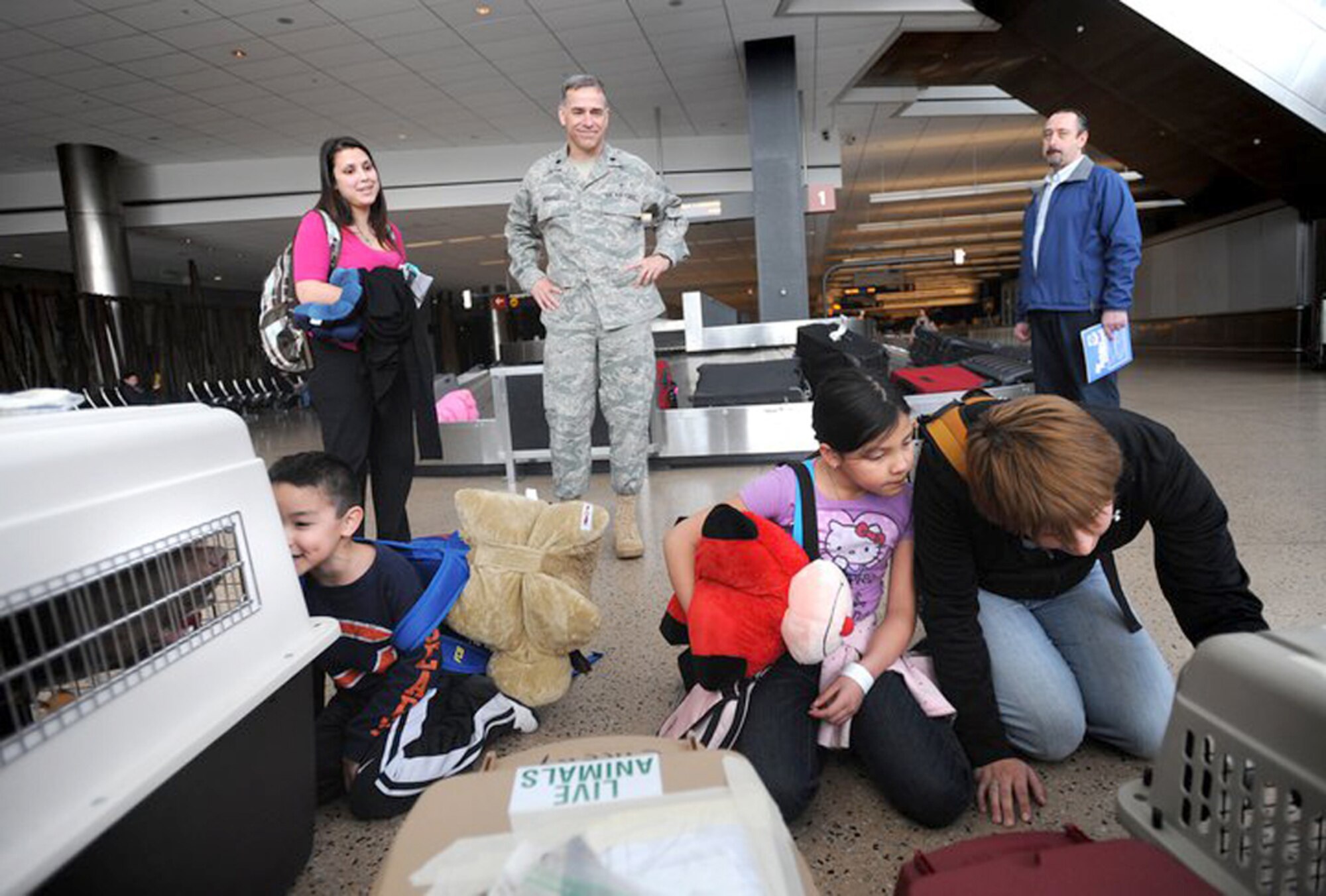 Caleb Velazquez (left), 5, his sister, Aubri, 8, and friend, Jess Alexander, check on Alexander's dogs as Monica Peck and Chaplain (Lt. Col.) Michael Husfelt  look on March 19, 2011, at Seattle-Tacoma International Airport, Wash. More than 230 Department of Defense personnel and family members landed there after leaving Japan. Chaplain Husfelt is the 627th Air Base Group chaplain. (U.S. Air Force photo)