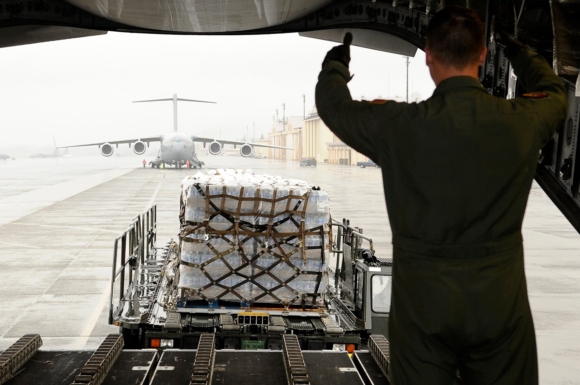 YOKOTA AIR BASE, Japan -- As part of Operation Tomodachi, Staff Sgt. Chris Baker guides a K-loader with humanitarian supplies behind a C-17 Globemaster III March 21, 2011. Crews unloaded the water and other relief items at Sendai Airport as American forces work closely with their Japanese counterparts to aid the people of Japan in the aftermath of an 8.9 earthquake, which hit Japan March 11. ?Tomodachi? is a Japanese word meaning ?friends.? Sergeant Baker is a member of the 535th Airlift Squadron, Joint Base Pearl Harbor-Hickam, Hawaii. (U.S. Air Force photo by/Master Sgt. Jeromy K. Cross/released) 