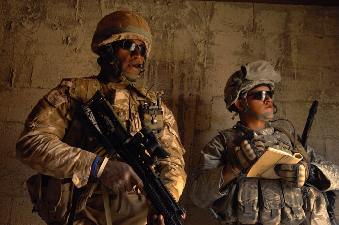 NEVADA TEST AND TRAINING RANGE -- Royal Air Force Senior Aircraftsman Tevita Ratuvuki, No.1 Squadron, Regiment 4 Force Protection Wing security forces, and U.S. Air Force Staff Sgt. Pablo Cancel, 820th Base Defense Group, stand guard during a meeting with a simulated Iraqi Village elder during a field training exercise at exercise Desert Eagle on the NTTR March 15. Desert Eagle is integrated training between No.1 Squadron, RAF Regiment and the 820th Base Defense Group Moody Air Force Base Ga., to improve both nations ability to work together during present and future contingencies. (U.S. Air Force photo by Airman 1st Class George Goslin)
