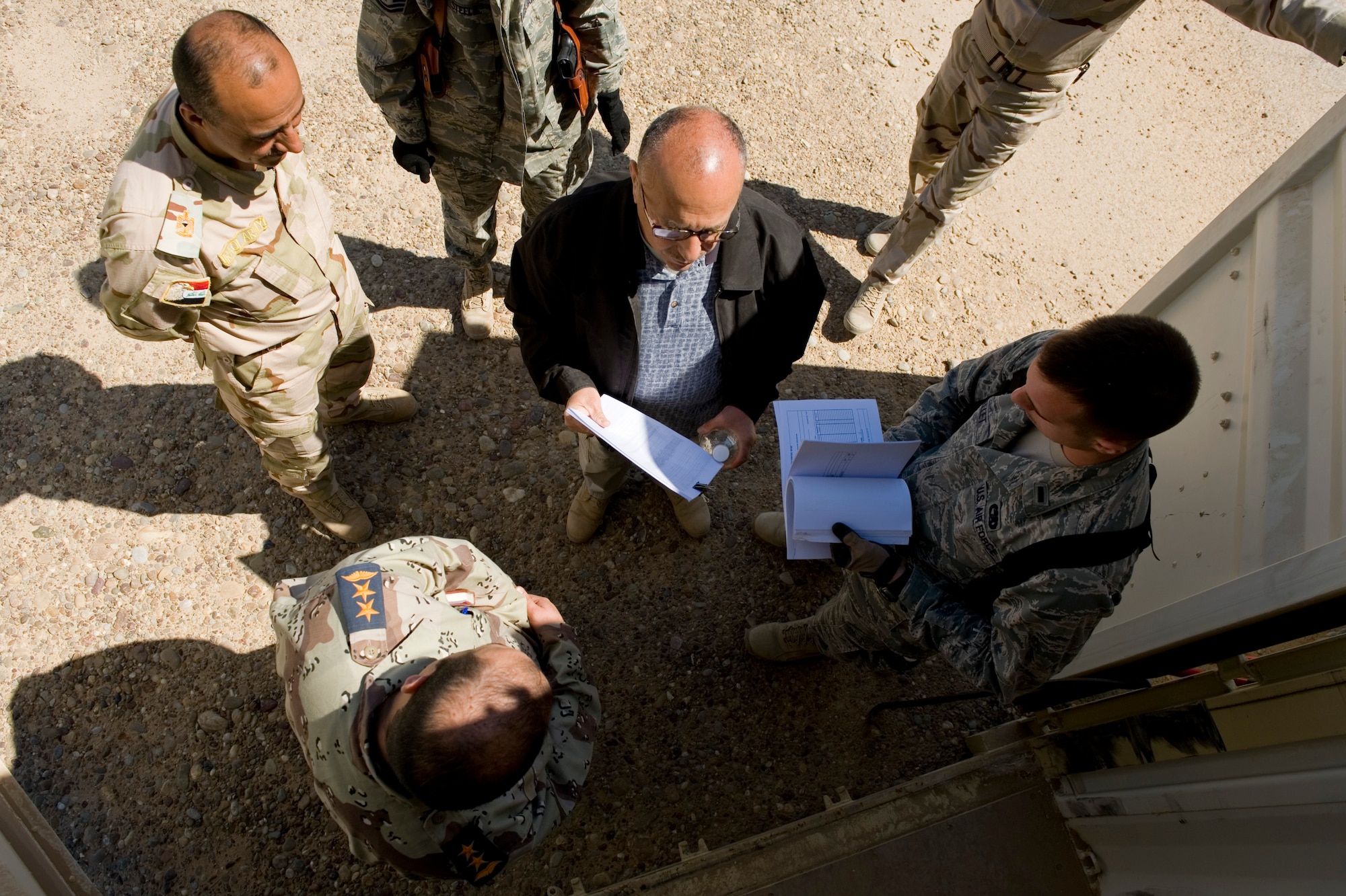 TIKRIT, Iraq -- 2nd Lt. John Ouellet III (right), Iraq Training and Advisory Mission-Air officer in charge of the foreign excess personal property program, speaks to Iraqi officers about the contents of a shipping container during a pre-transfer inventory March 17. The transfer, involving five crates and more than $300,000 of equipment, is part of more than $7 million in assets being transferred in order to save money on shipping costs and strengthen the U.S. partnership with Iraq. Lieutenant Ouellet is deployed from the 60th Aerial Port Squadron, Travis Air Force Base, Calif., and is a native of Los Gatos, Calif. (U.S. Air Force photo by Staff Sgt. Levi Riendeau)