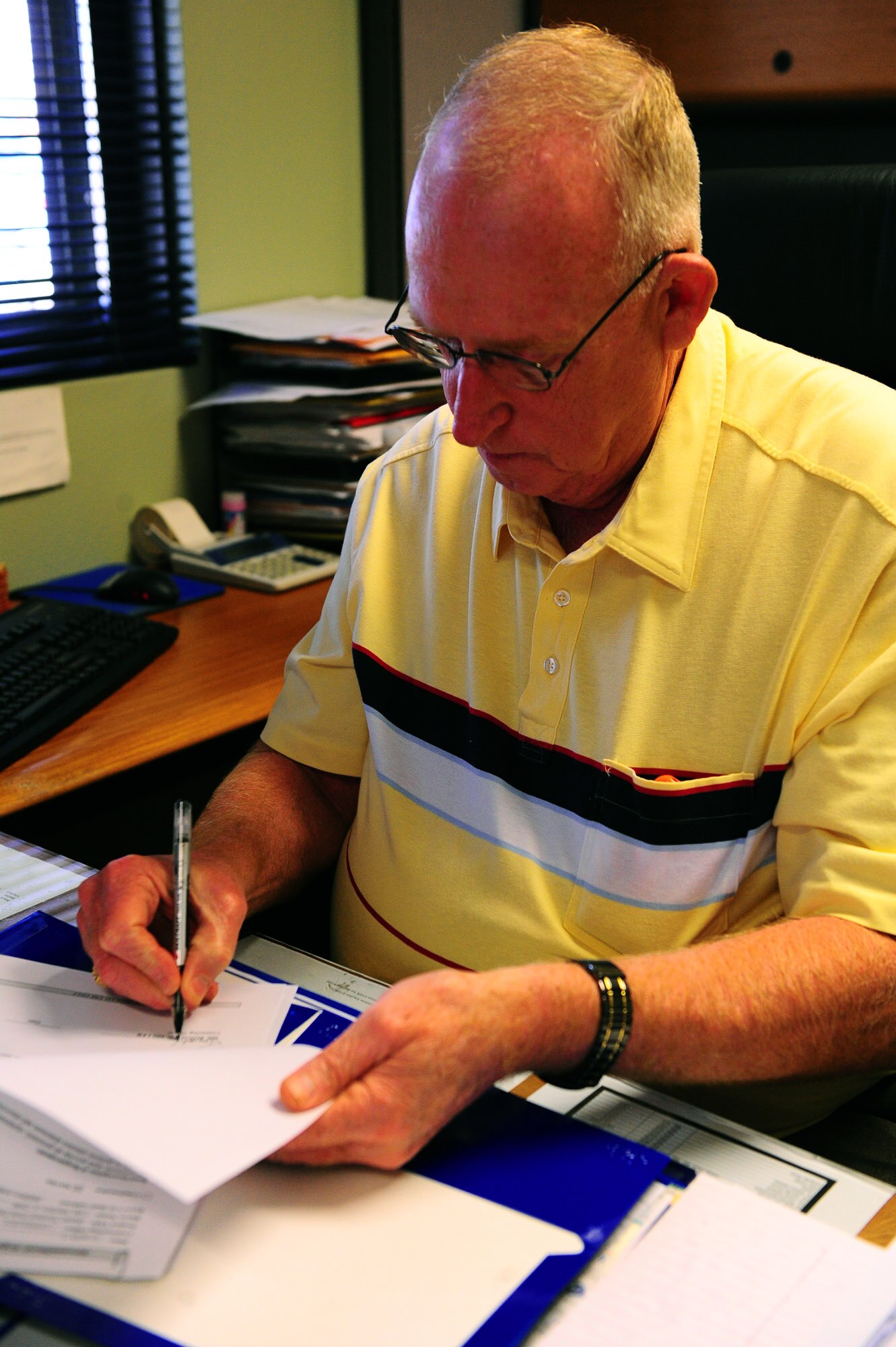 Ronald G. Miller, 7th Contracting Squadron chief of infrastructure, signs paperwork March 16 at his desk here.  Mr. Miller has been at Dyess more than 25 years and currently oversees a team of 35 civilians, officers and Airmen from the 7 CONS, a team he has praised as the main contributors to the award.(U.S. Air Force photo/ Airman First Class Courtney Moses)