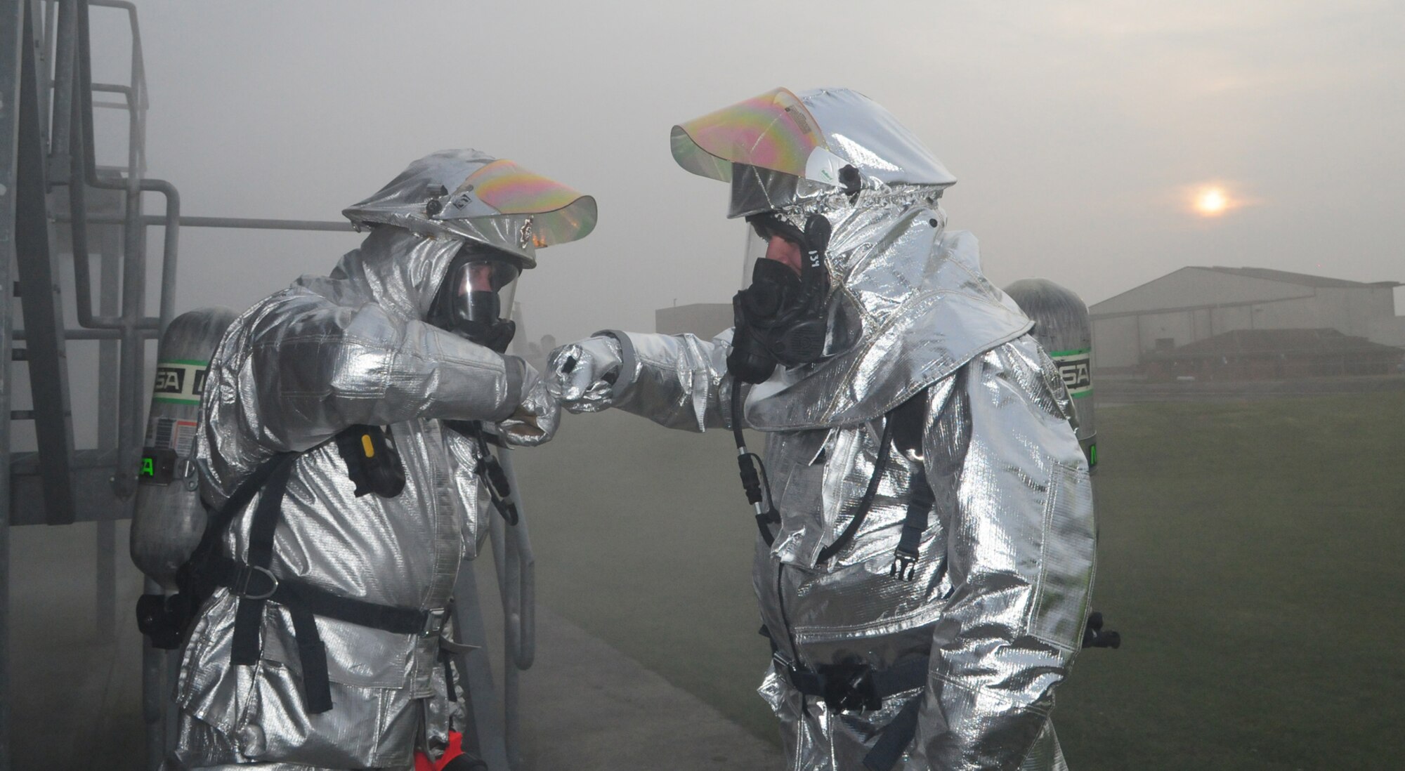 RAF MILDENHALL, England -- Crew manager Simon Evans, left, 100th Civil Engineer Squadron Fire Department, and Nigel McCurdy, Forest Heath District Council strategic director and 100th CES honorary commander, encourage each other before heading into the smoke house here March 17, 2011. Smoke filled the nearby area before they went in, as Col. David Doe, 100th Mission Support Squadron commander, went inside the smoke house first to bring out a mannequin as part of a training rescue scenario. Mr. McCurdy and Colonel Doe spent time training with the firefighters to gain an understanding of the job they do. (U.S. Air Force photo/Karen Abeyasekere)