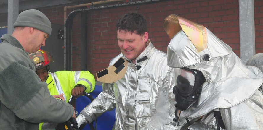 RAF MILDENHALL, England -- Master Sgt. Christopher Lanier and Tech. Sgt. Corey Coleman, both 100th Civil Engineer Squadron Fire Department, help Col. David Doe, 100th Mission Support Group commander, remove his mask and breathing apparatus after being in the smoke house performing a rescue of a simulated casualty with Tech. Sgt. Adam Crowe, right, 100th CES Fire Department, March 17, 2011. Colonel Doe, along with Nigel McCurdy, Forest Heath District Council strategic director and 100th CES honorary commander, had the chance to train with the firefighters at the live fire trainer. (U.S. Air Force photo/Karen Abeyasekere)