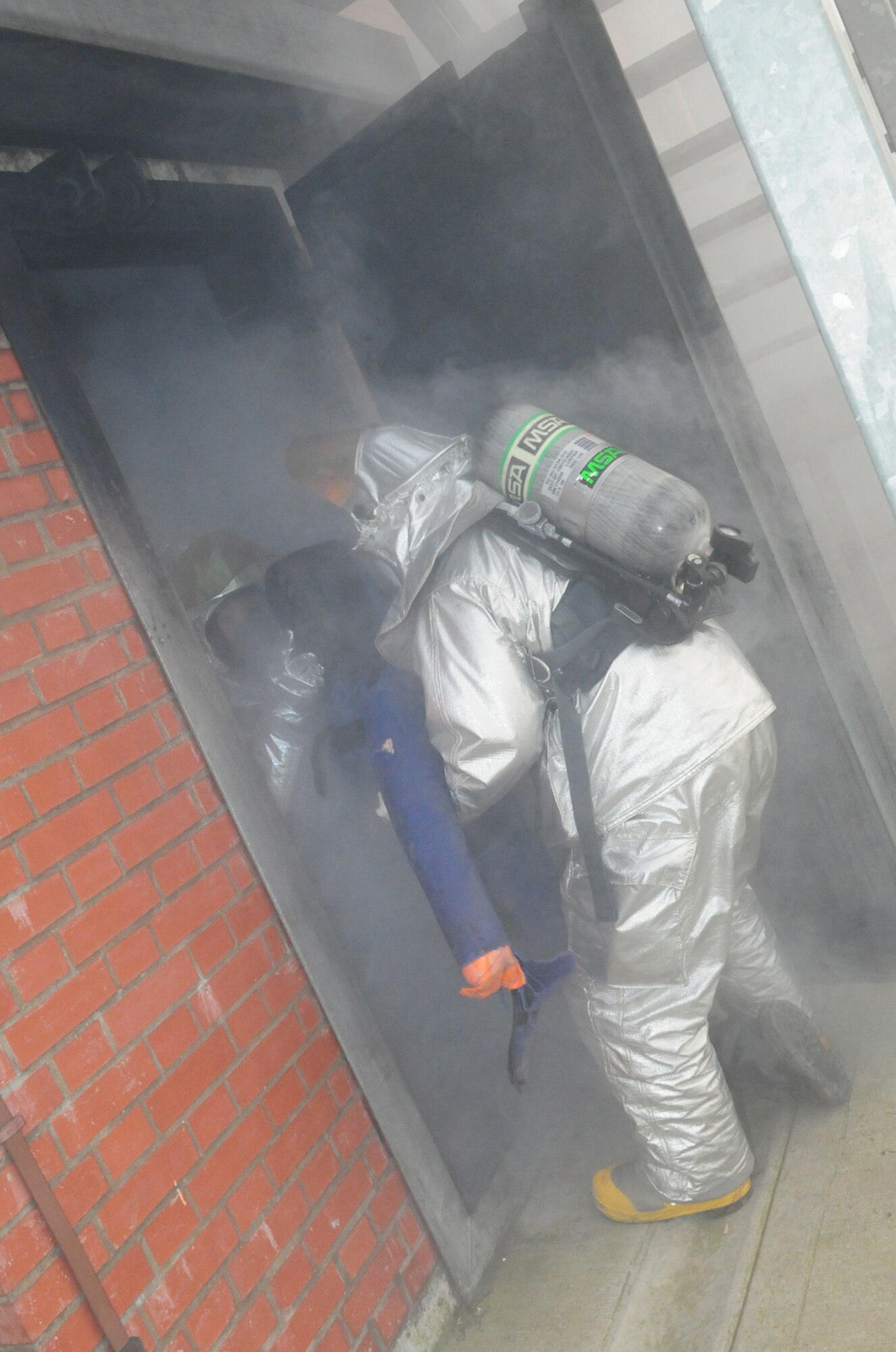 RAF MILDENHALL, England -- Tech. Sgt. Adam Crowe, 100th Civil Engineer Squadron Fire Department, right, and Col. David Doe, 100th Mission Support Group commander, perform a simulated rescue as they bring a mannequin out of the smoke house during a training session March 17, 2011. Colonel Doe, along with Nigel McCurdy, Forest Heath District Council stratigic director and 100th CES honorary commander, spent time training with the firefighters at the live fire trainer and smoke house get an insight into what the firefighters do and how they train. (U.S. Air Force photo/Karen Abeyasekere)