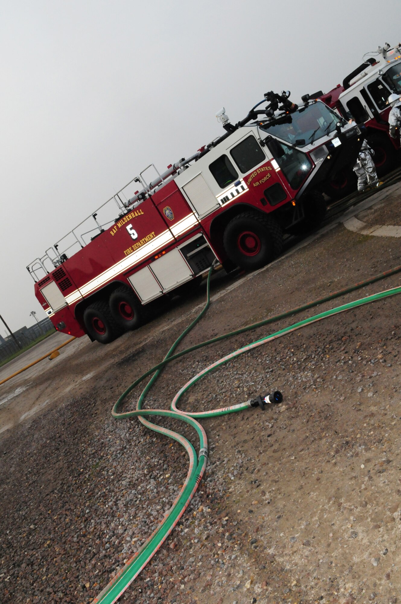 RAF MILDENHALL, England -- Firefighters brought several firetrucks out to the live fire trainer here March 17, 2011, for a training exercise. Col. David Doe, 100th Mission Support Group commander, and Nigel McCurdy, Forest Heath District Council strategic director and 100th Civil Engineer Squadron honorary commander, donned protective gear and took part in the training where they helped put out a fire on a mock aircraft. (U.S. Air Force photo/Karen Abeyasekere)