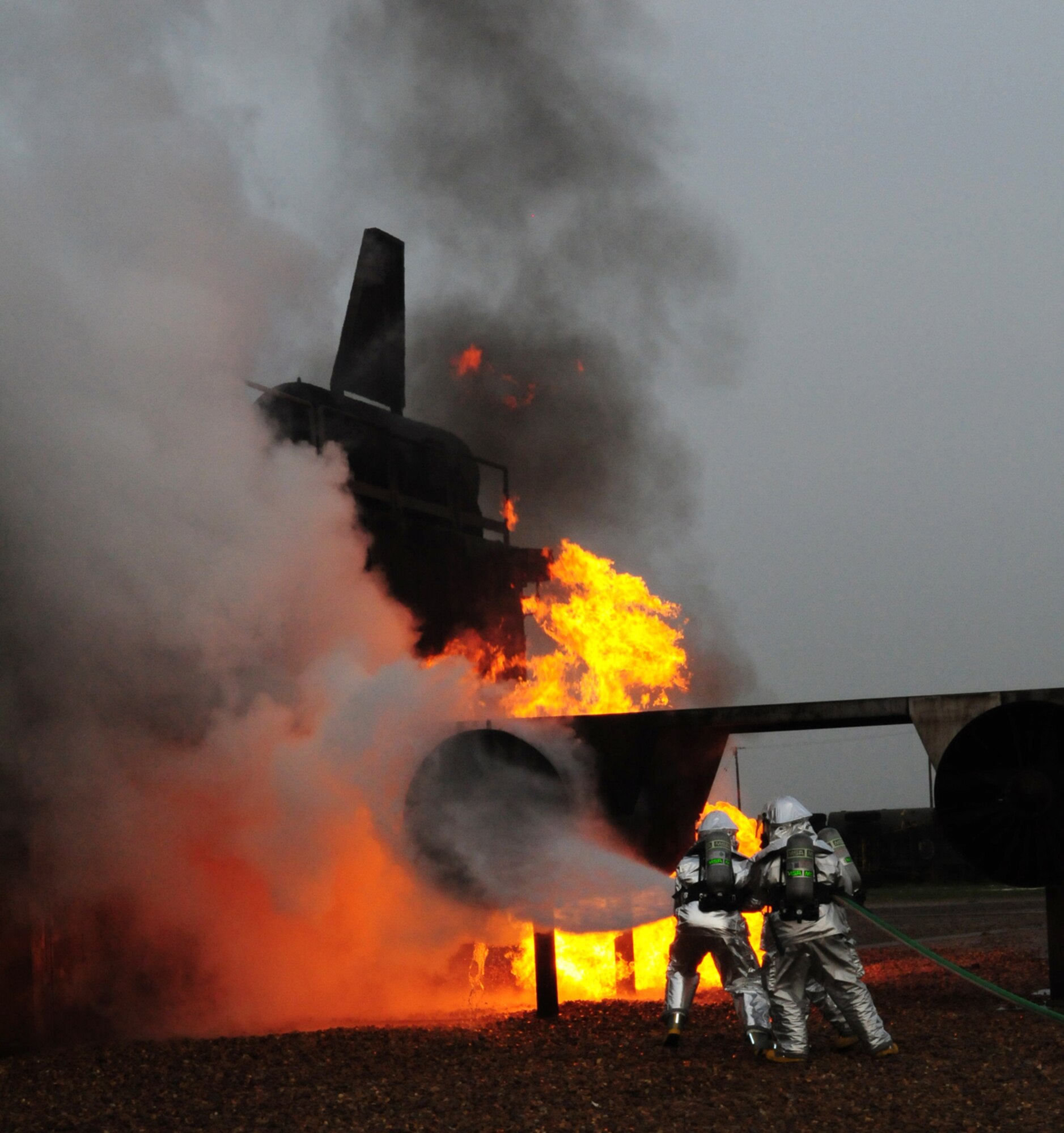 RAF MILDENHALL, England -- Colonel David Doe, 100th Mission Support Group commander and crew managers Barry Clark and Simon Evans, both 100th Civil Engineer Squadron Fire Department, move a pressurized hose from side-to-side to put out a fire on a mock aircraft engine March 17, 2011. Colonel Doe and Nigel McCurdy, 100th CES honorary commander, got the opportunity to take a turn at the live fire trainer and assist in putting out a fire. Mr. McCurdy is a member of RAF Mildenhall's Honorary Commanders' Program, which is vital to foster and maintain healthy British-American relationships. (U.S. Air Force photo/Karen Abeyasekere)