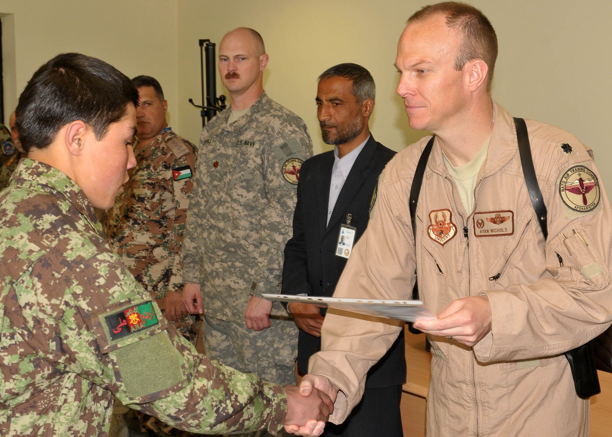 KABUL, Afghanistan - Lt. Col. Ryan Nichols, Commander of the 738th Air Expeditionary Advisory Squadron, presents a certificate to a graduating member of the Afghan Air Force from 
the Pohantoon-e-Hawayee, the Afghan Air Force's "Big Air School", on the Afghan Air Force base in Kabul, Afghanistan March 17. (U.S. Navy photo by Mass Communications Specialist 3rd Class Jared E. Walker)
