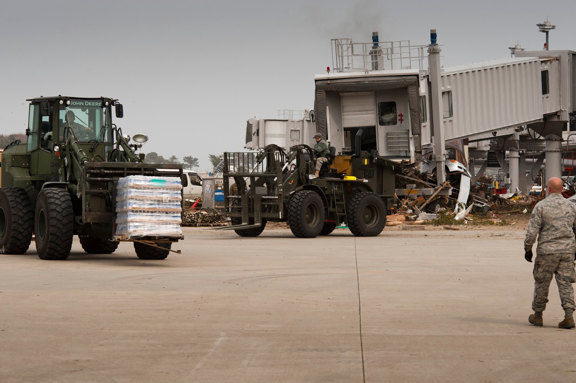 Members of the 353rd Special Operations Group drive forklifts carrying pallets of freshwater to be loaded onto Japan Ground Self-Defense Force trucks at Sendai Airport, Japan, March 20. The 320th Special Tactics Squadron manages the airfield with the help of the 353rd SOG, Marines, JGSDF and other Japanese agencies. Sendai Airport has become a main hub for bringing humanitarian aid to those affected by the earthquake and tsunami from March 11. (U.S. Air Force photo/Staff Sgt. Samuel Morse)