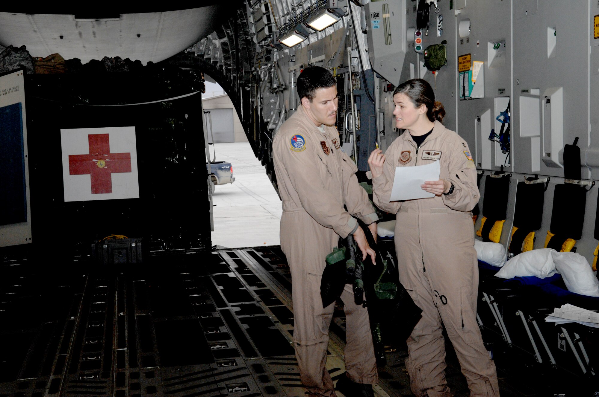 Staff Sgt. Jordan Piper and Capt. Sarah Morton, both aeromedical evacuation crew members, discuss patient information prior to receiving patients aboard a C-17. The crew was headed to Landstuhl Medical Center from Bagram Airfield, Afghanistan, so their patients could receive further medical care. (U.S. Air Force photo/Senior Airman Amber R. Kelly-Herard) 