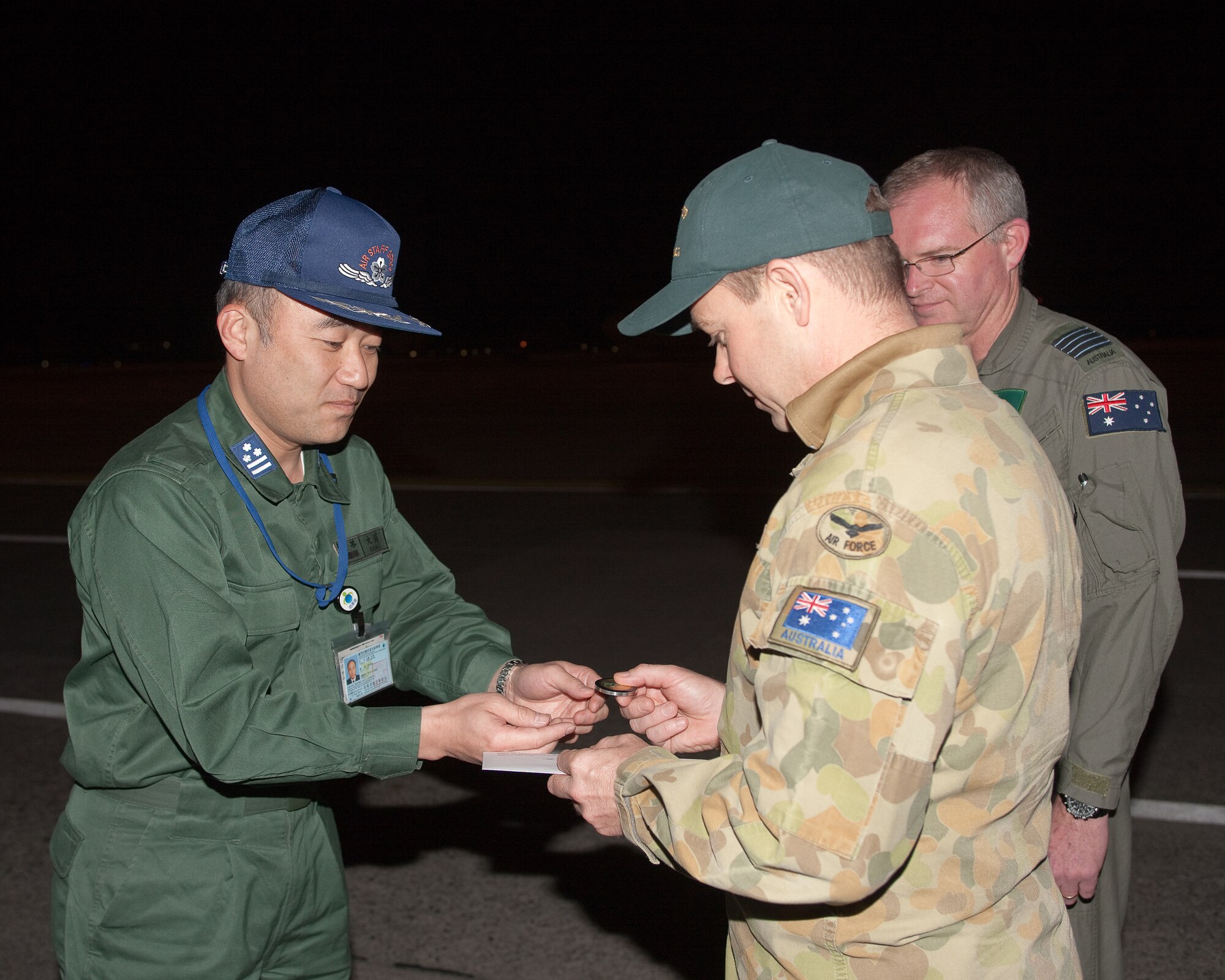 YOKOTA AIR BASE, Japan -- Col. Hiroyoshi Ooura (left), Japan Air Self-Defense Force Air Staff Office, gives his coin to Wing Commander David Howard, Royal Australian Air Force, in gratitude for the RAAF's participation in recent humanitarian relief operations following the earthquake and tsunami that struck Japan March 11. Amberley's 36th Squadron sent two RAAF air crews and a C-17 to Japan to fly numerous humanitarian missions. (U.S. Air Force photo/Osakabe Yasuo)