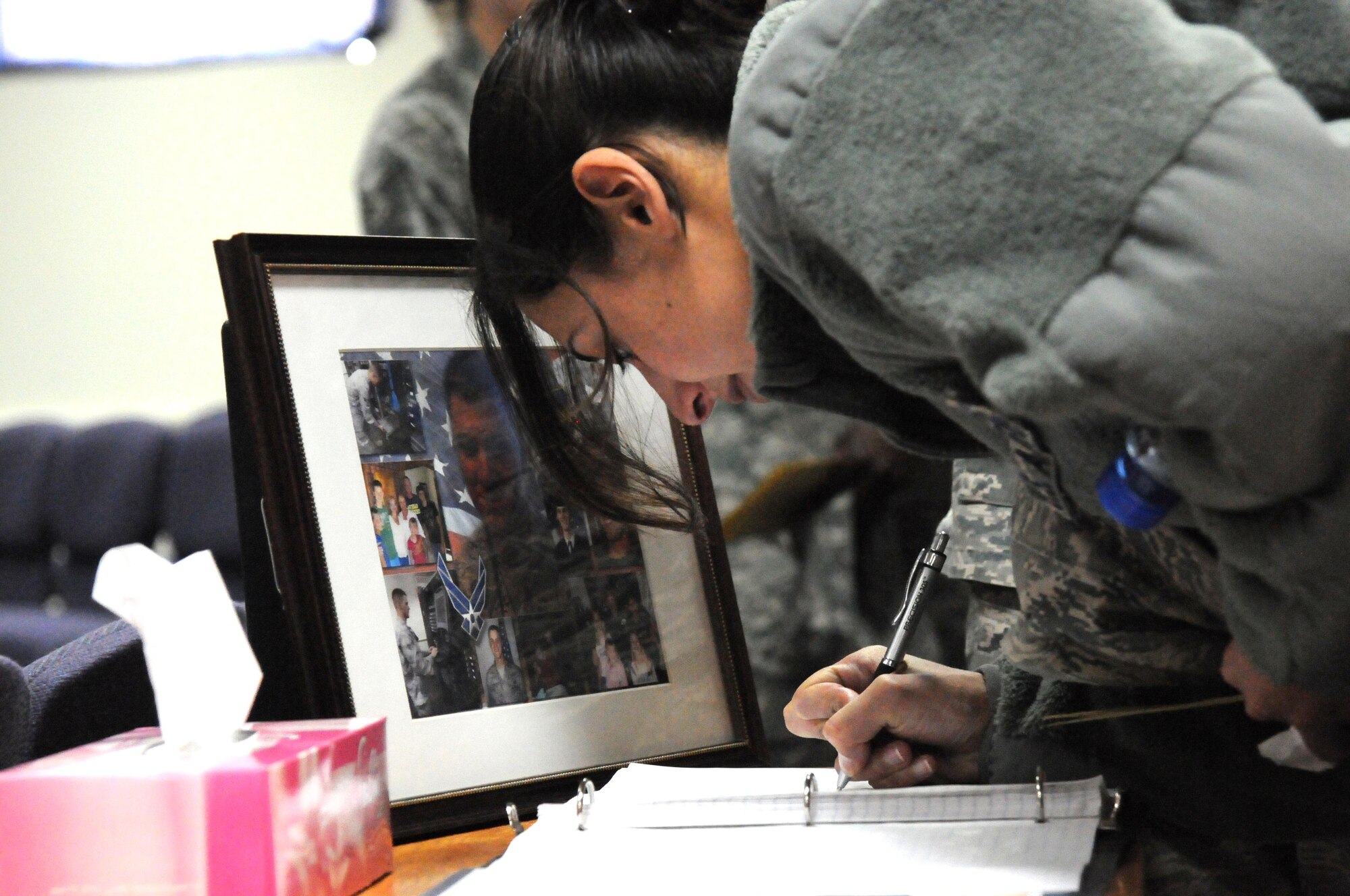 Airman 1st Class Shanee Gamliel, 386th Expeditionary Communications Squadron, signs a memory book after a memorial service March 19 at an undisclosed location in Southwest Asia. The 386th Air Expeditionary Wing held a memorial service to remember the life of Senior Airman Michael J. Hinkle II, 24, who died from a non-combat related incident March 16. (U.S. Air Force photo by Staff Sgt. Patrice Clarke)